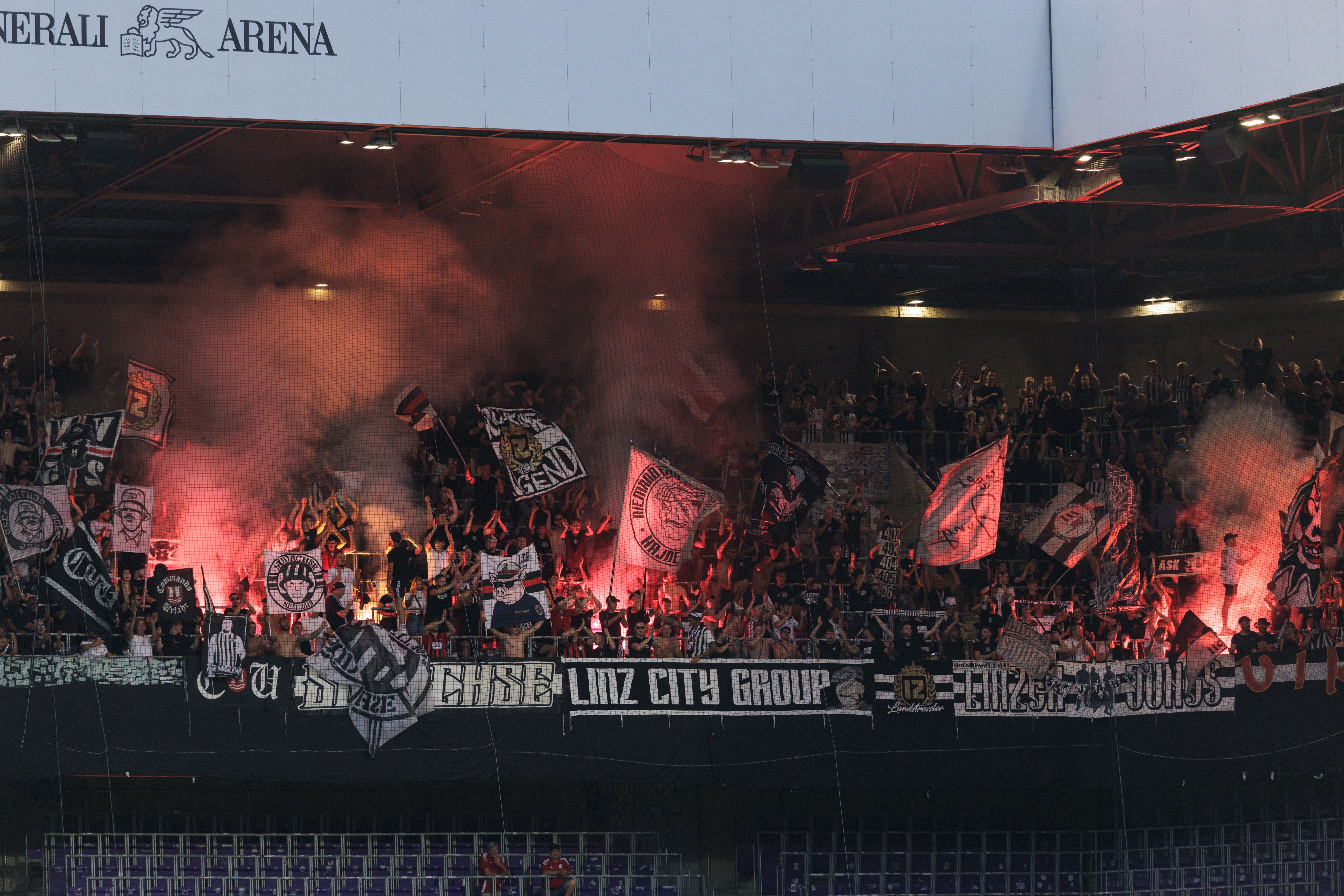 LASK-Fans zünden Bengalos und schwenken Fahnen im Stadion bei einem Fußballspiel.