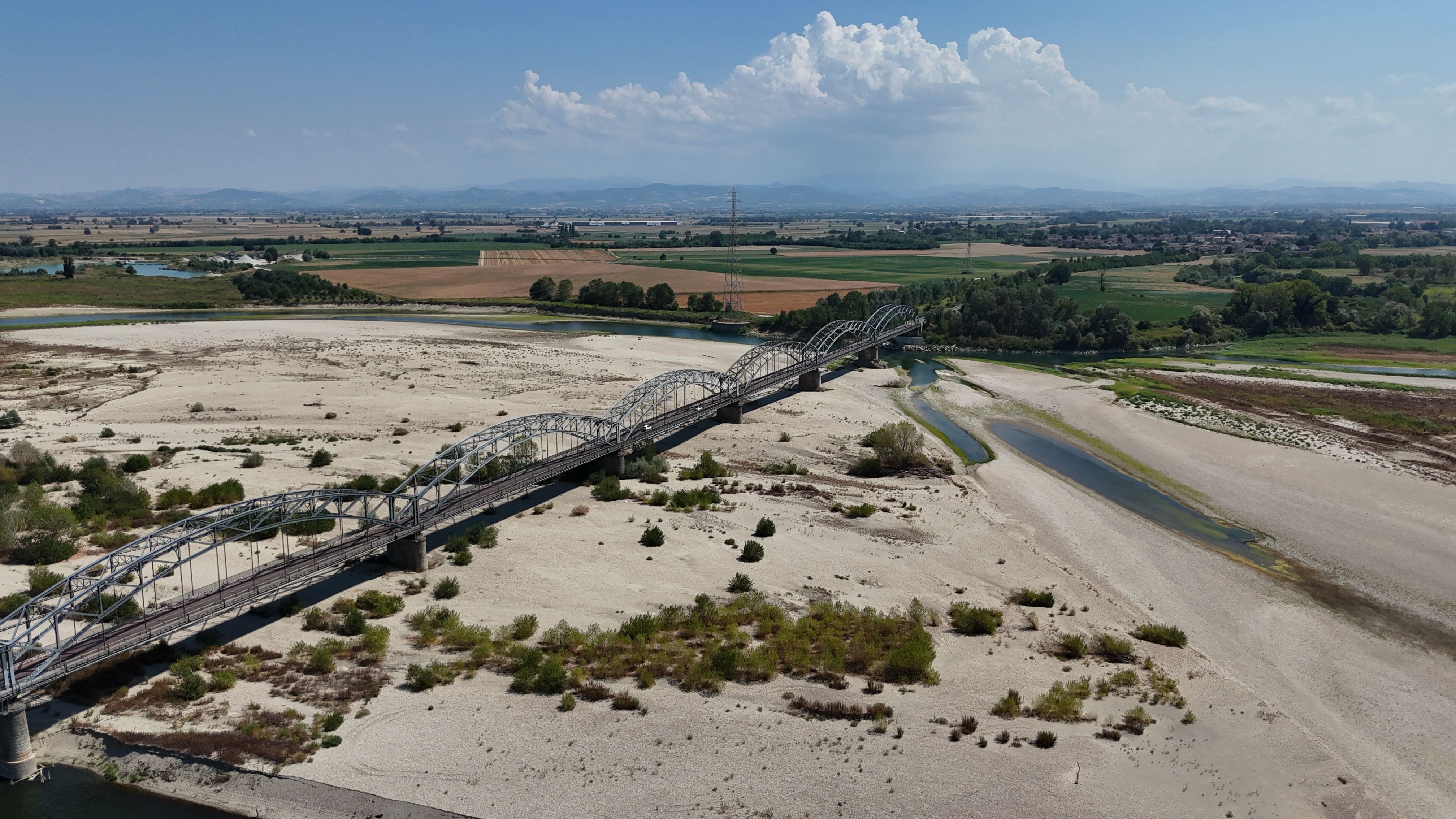 Luftaufnahme einer Eisenbahnbrücke über fast ausgetrocknete Sandbänke des Po bei Mezzana Bigli.