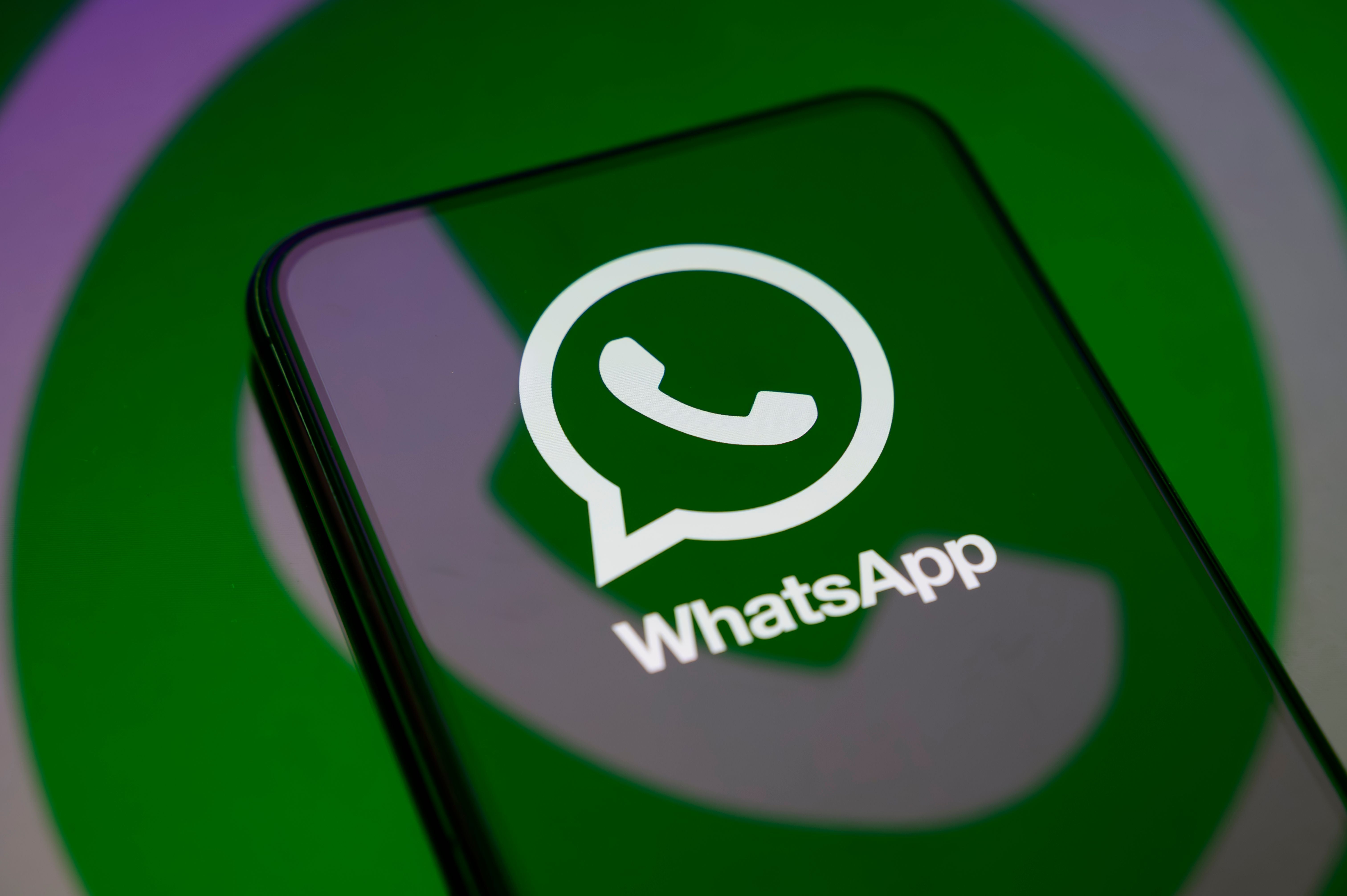 Das WhatsApp-Logo ist groß auf dem Display eines Smartphones zu sehen.