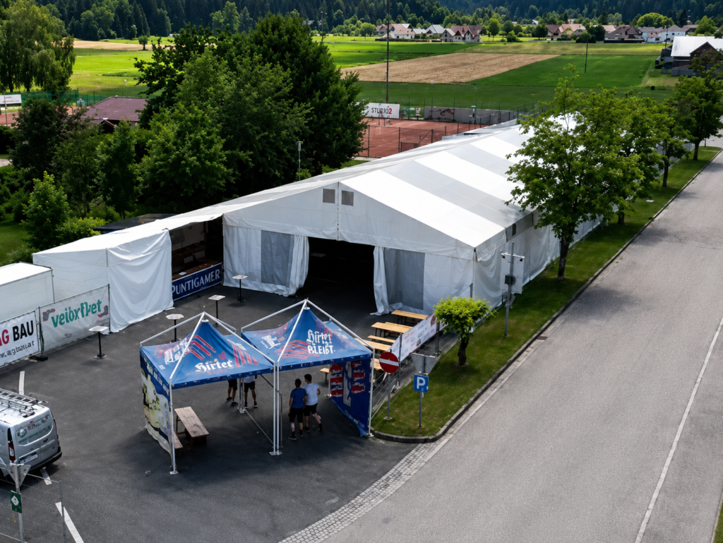 Großes Festzelt mit Bierständen und Pavillons auf einem Parkplatz beim Feuerwehrfest in Globasnitz.