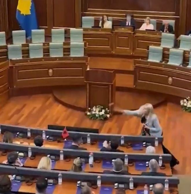 Eine Frau wirft einen Gegenstand in einem Sitzungssaal des Parlaments von Kosovo.