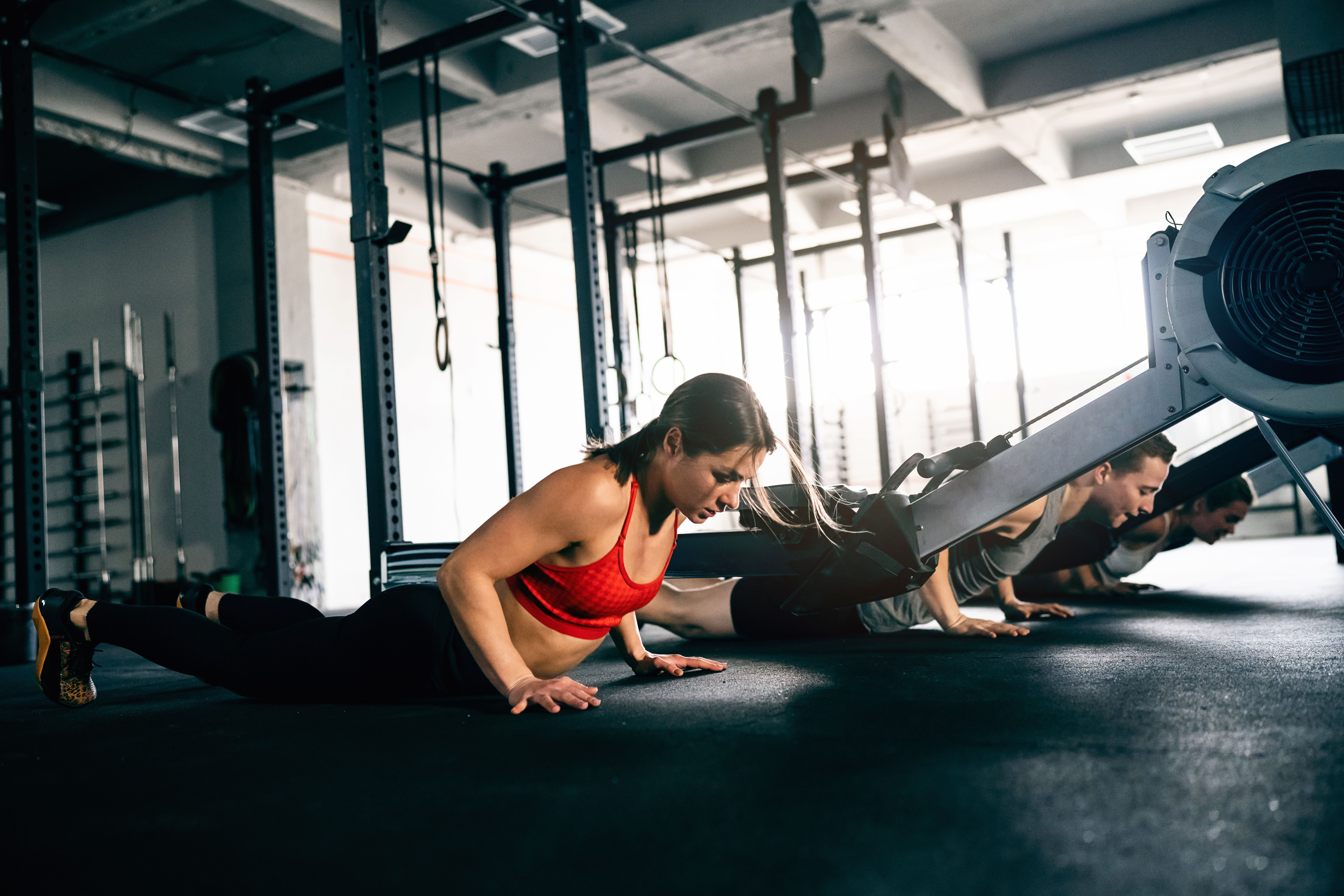 Mehrere Sportler machen gemeinsam Burpees in einem Fitnessstudio.