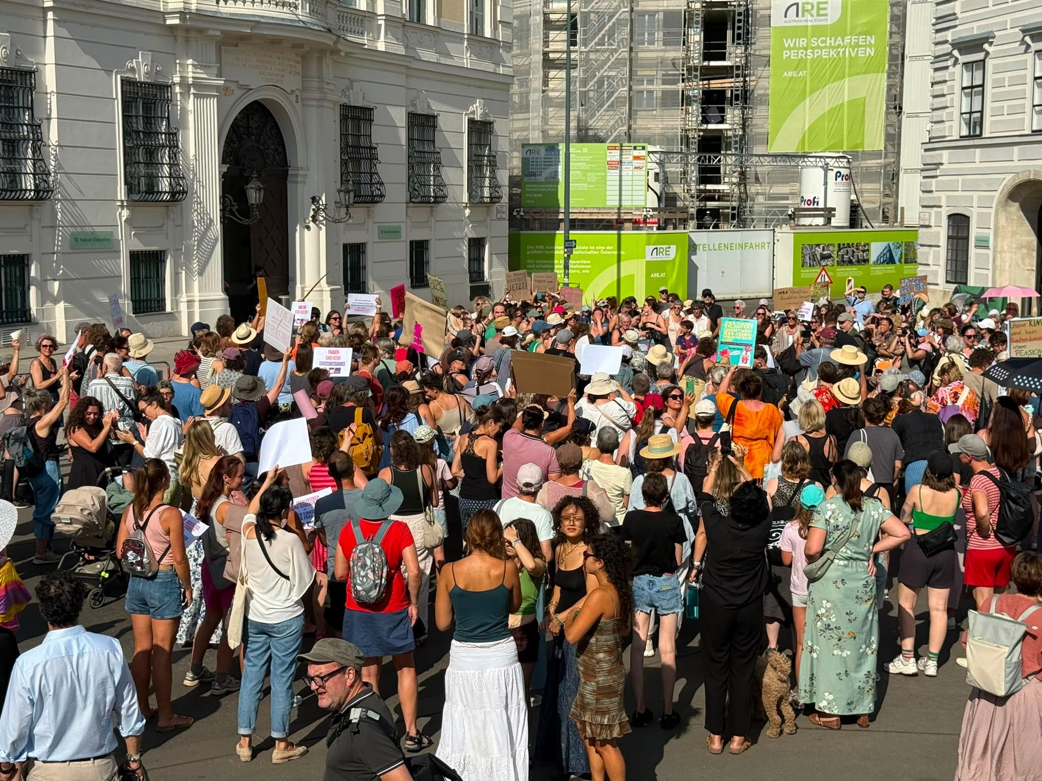 Viele Menschen versammeln sich bei einer Frauen-Demo, halten Schilder und Plakate hoch.