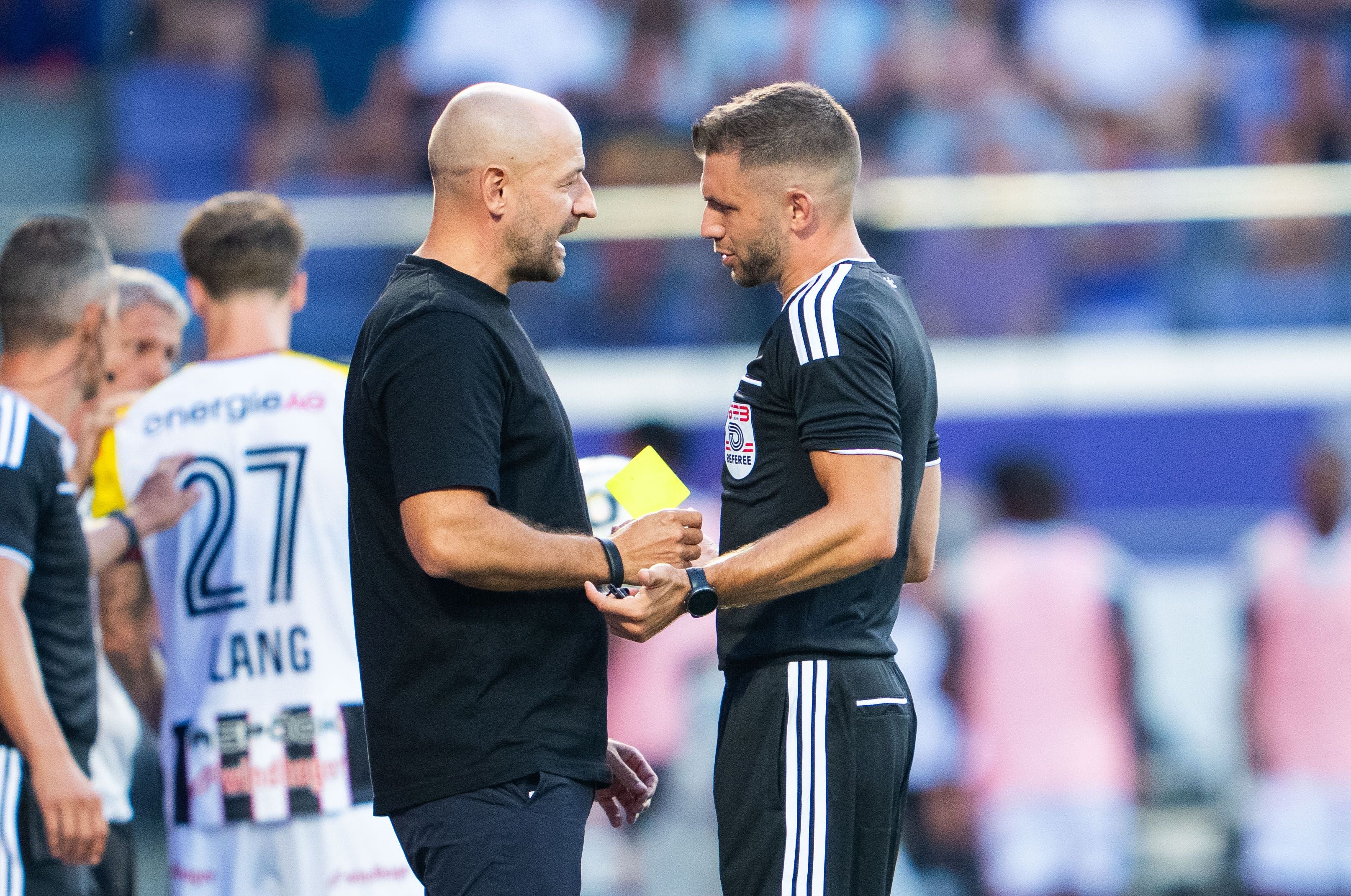 Ein Schiedsrichter zeigt Trainer Stephan Helm während eines Fußballspiels die gelbe Karte.