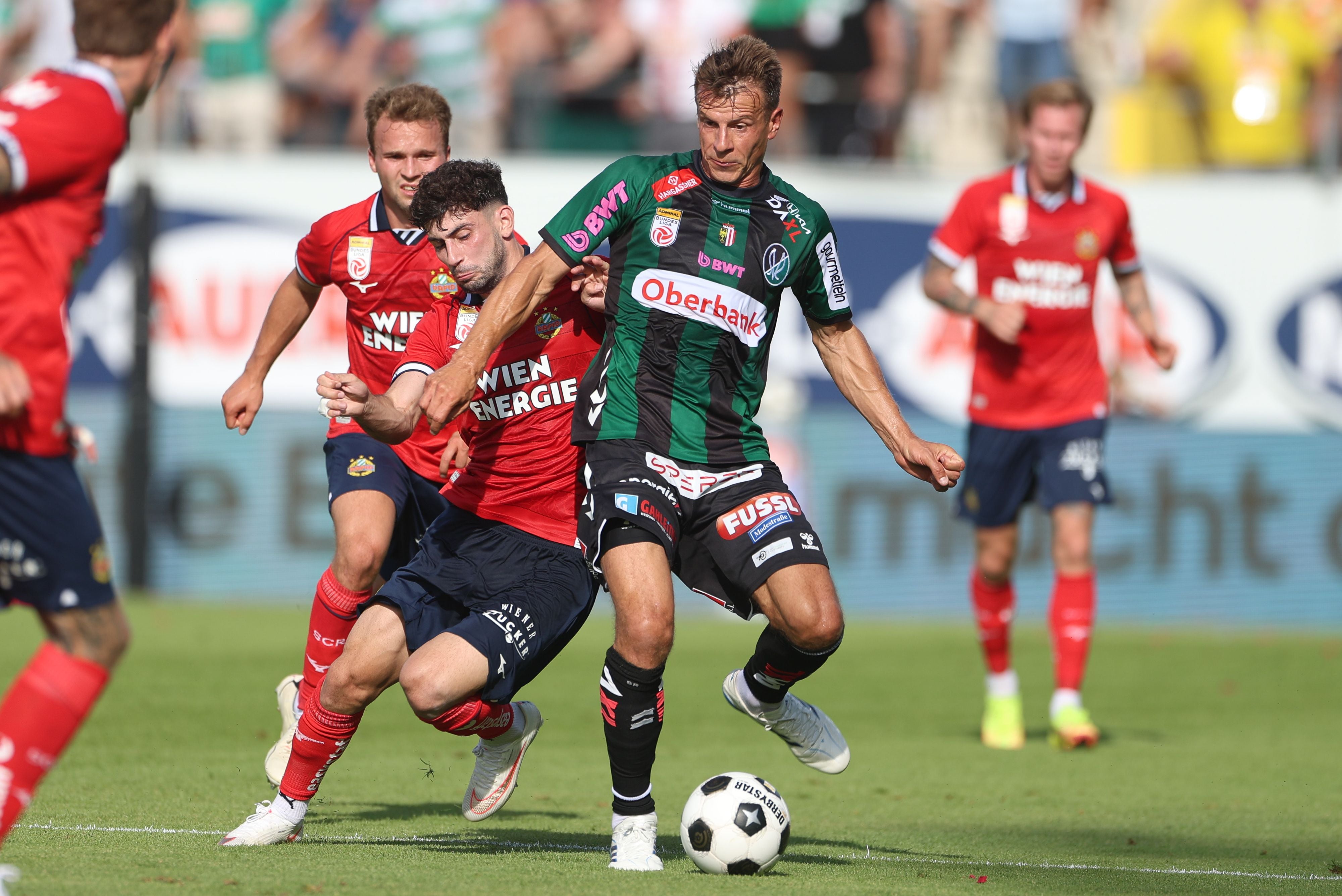 Zwei Fußballspieler kämpfen während eines Spiels intensiv um den Ball.