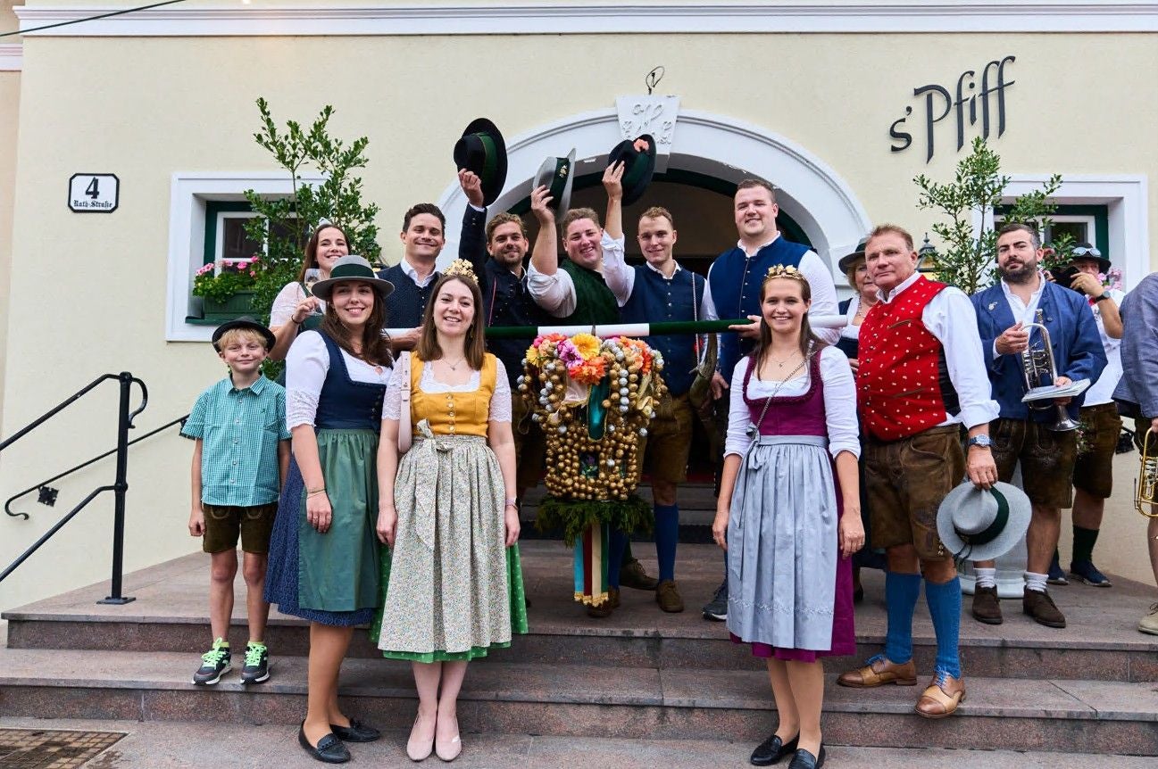 Gruppe in traditioneller Tracht beim Neustifter Kirtag vor einem geschmückten Hauseingang.
