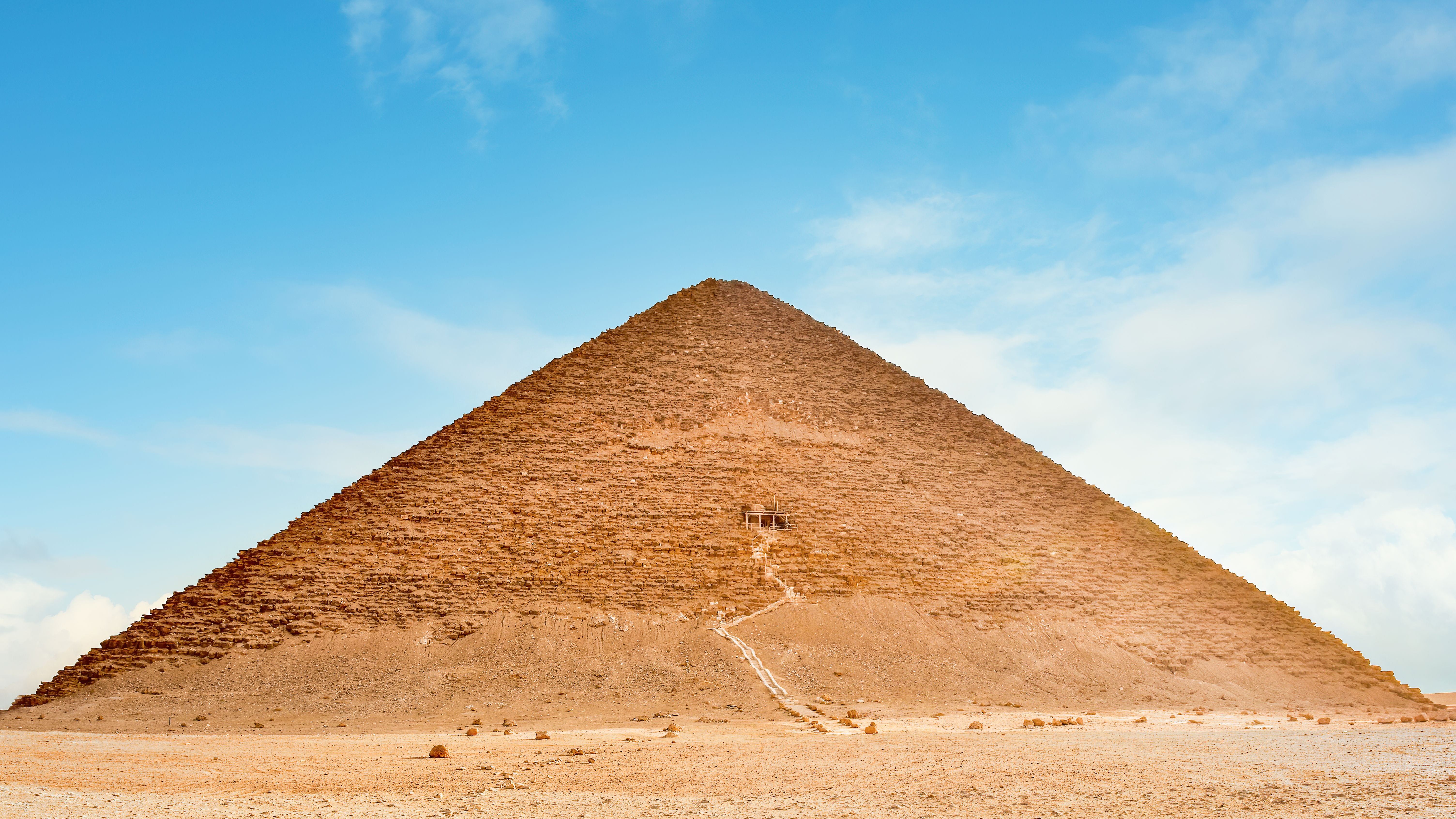 Die Rote Pyramide in Dahschur, Ägypten, steht vor blauem Himmel in der Wüste.