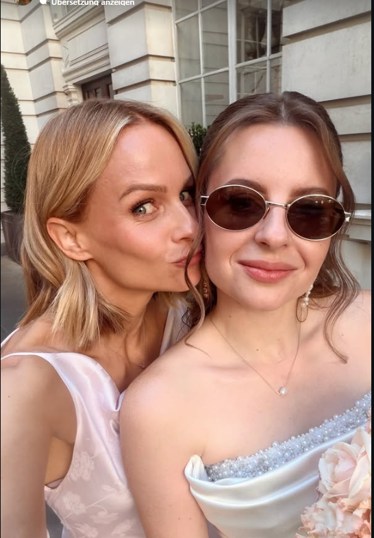 Zwei Frauen machen ein Selfie auf einer Hochzeit, eine küsst die andere auf die Wange.