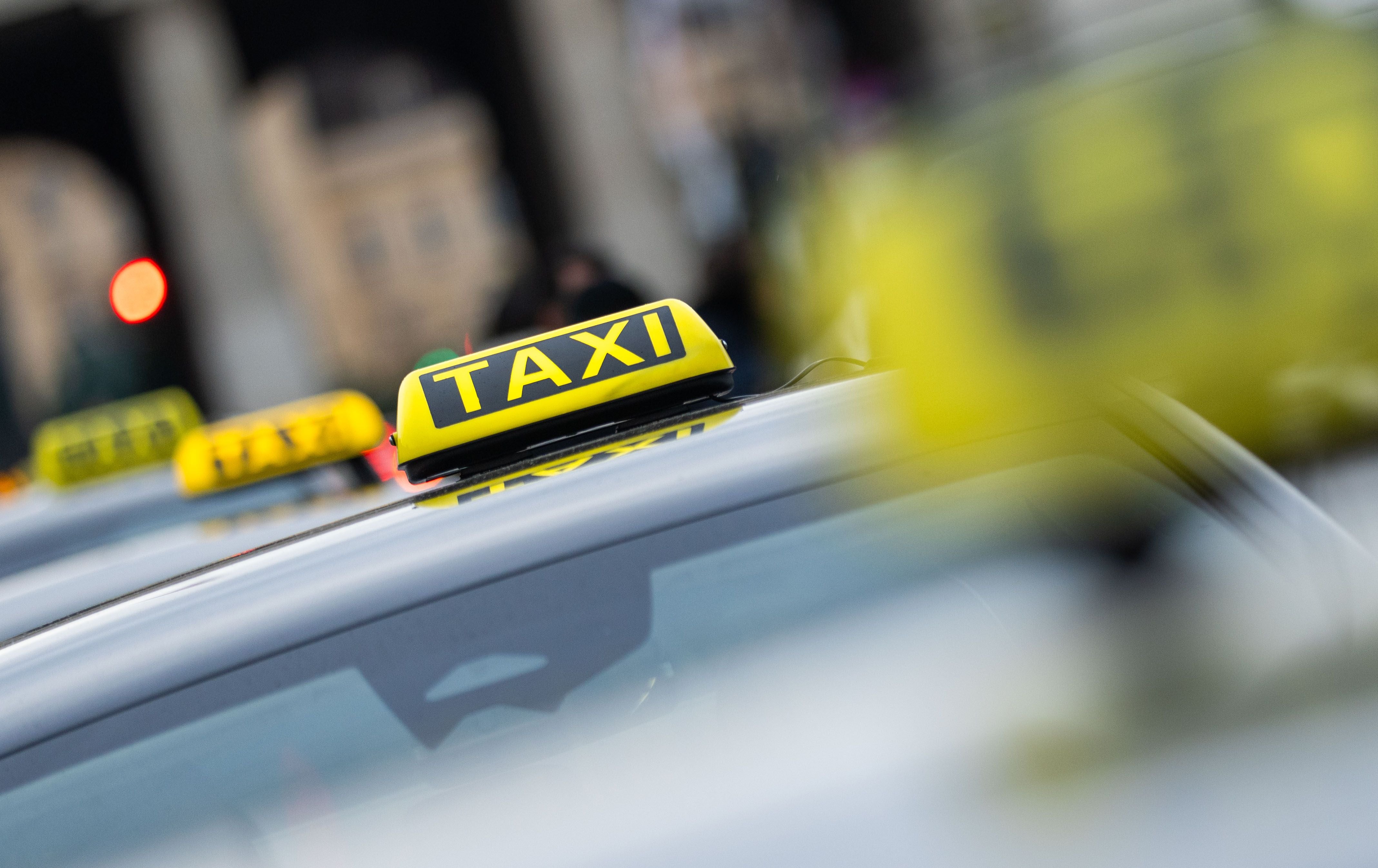 Mehrere gelbe Taxi-Schilder auf Autos während einer Demonstration in Wien.