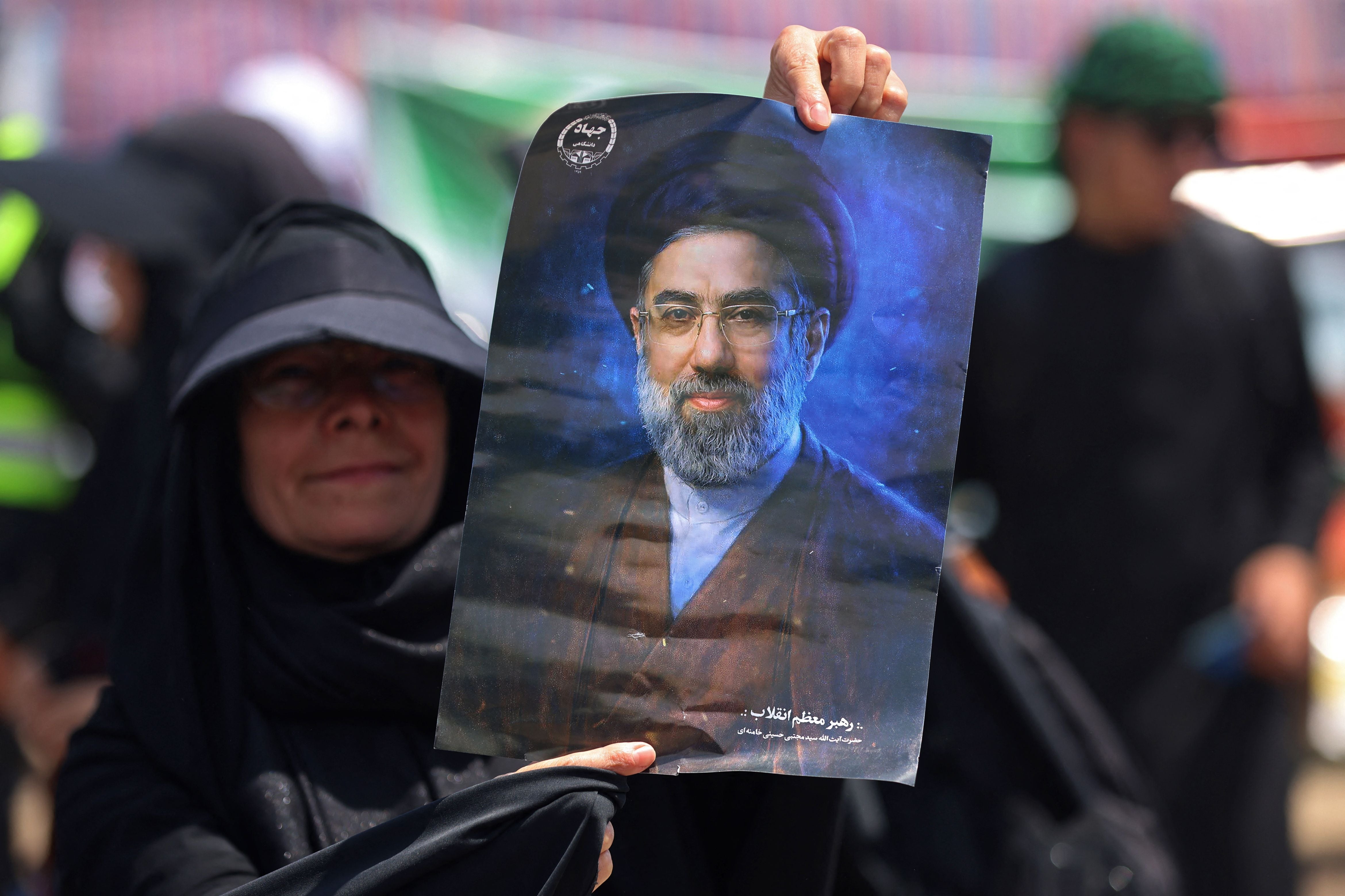 Eine Iranerin hält ein Porträt Mojtaba Khameneis hoch.