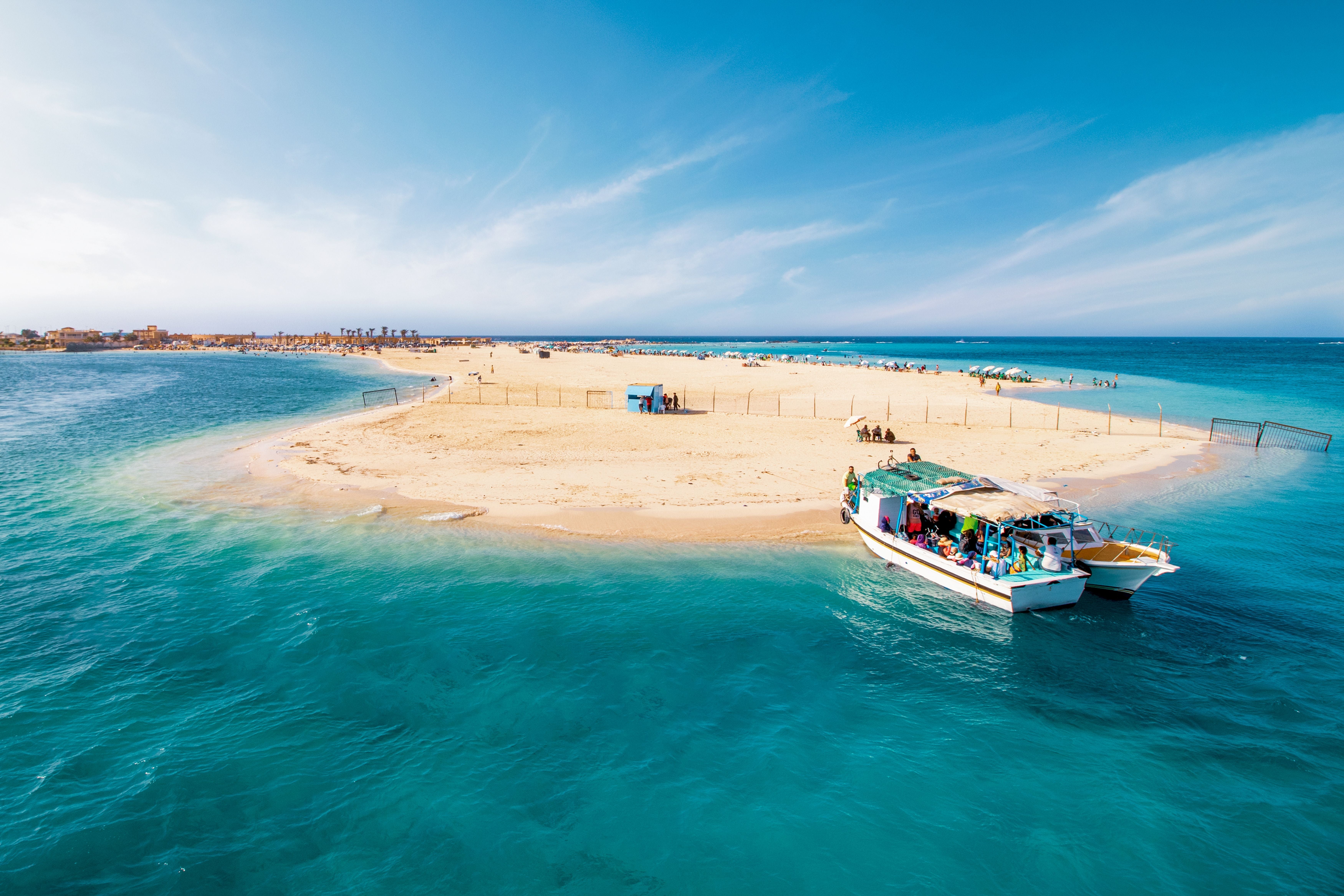 Luftaufnahme vom Gharam Beach in Marsa Matrouh mit türkisfarbenem Wasser und Touristenboot.
