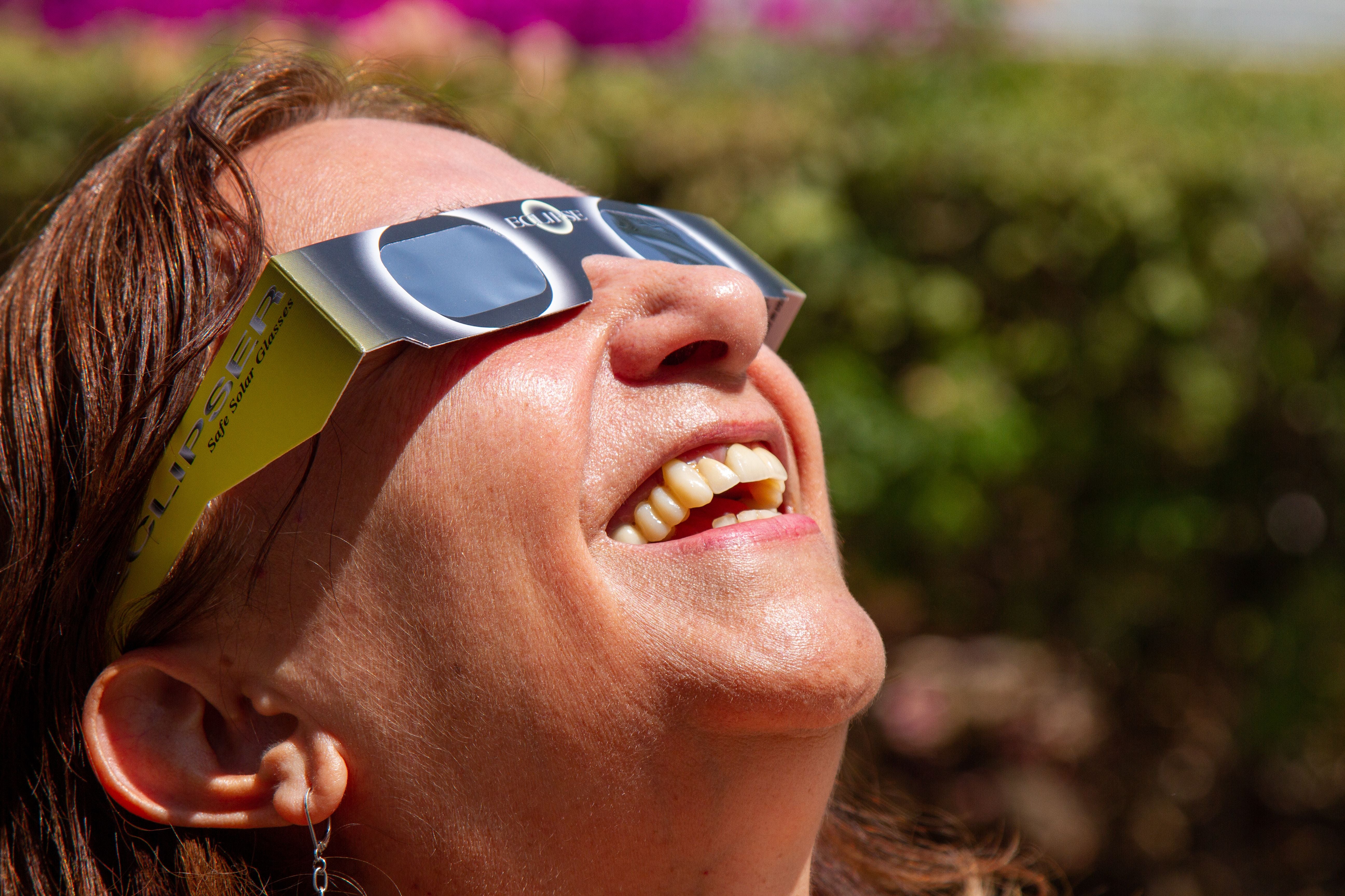 Frau beobachtet mit Sonnenfinsternisbrille eine totale Sonnenfinsternis im Freien.