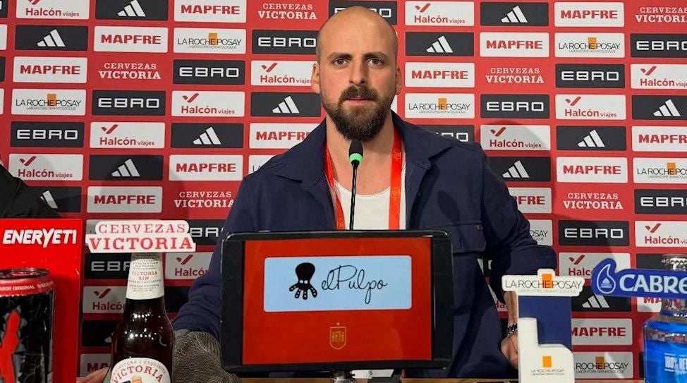 Burhan Can Terzi einer Pressekonferenz vor einem Mikrofon und Werbetafeln.