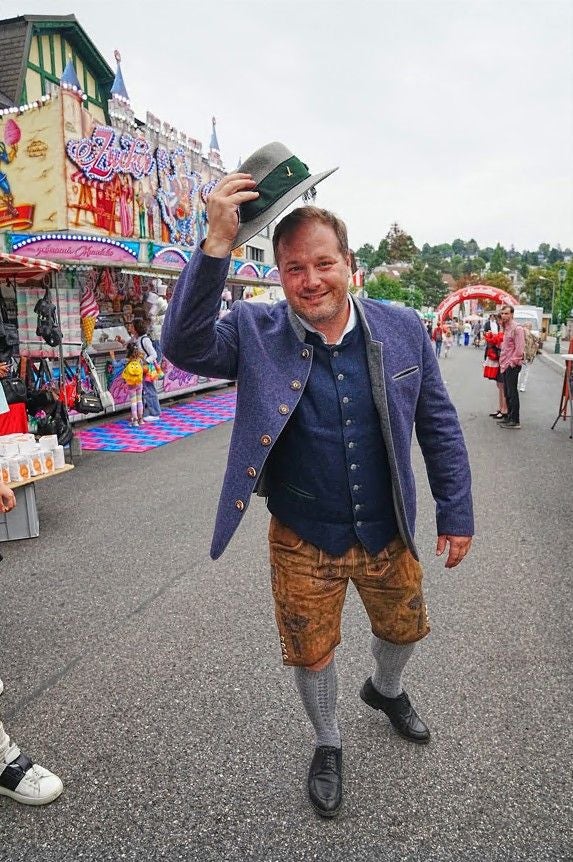 Mann in Tracht hebt seinen Hut auf einem Jahrmarkt beim Neustifter Kirtag.