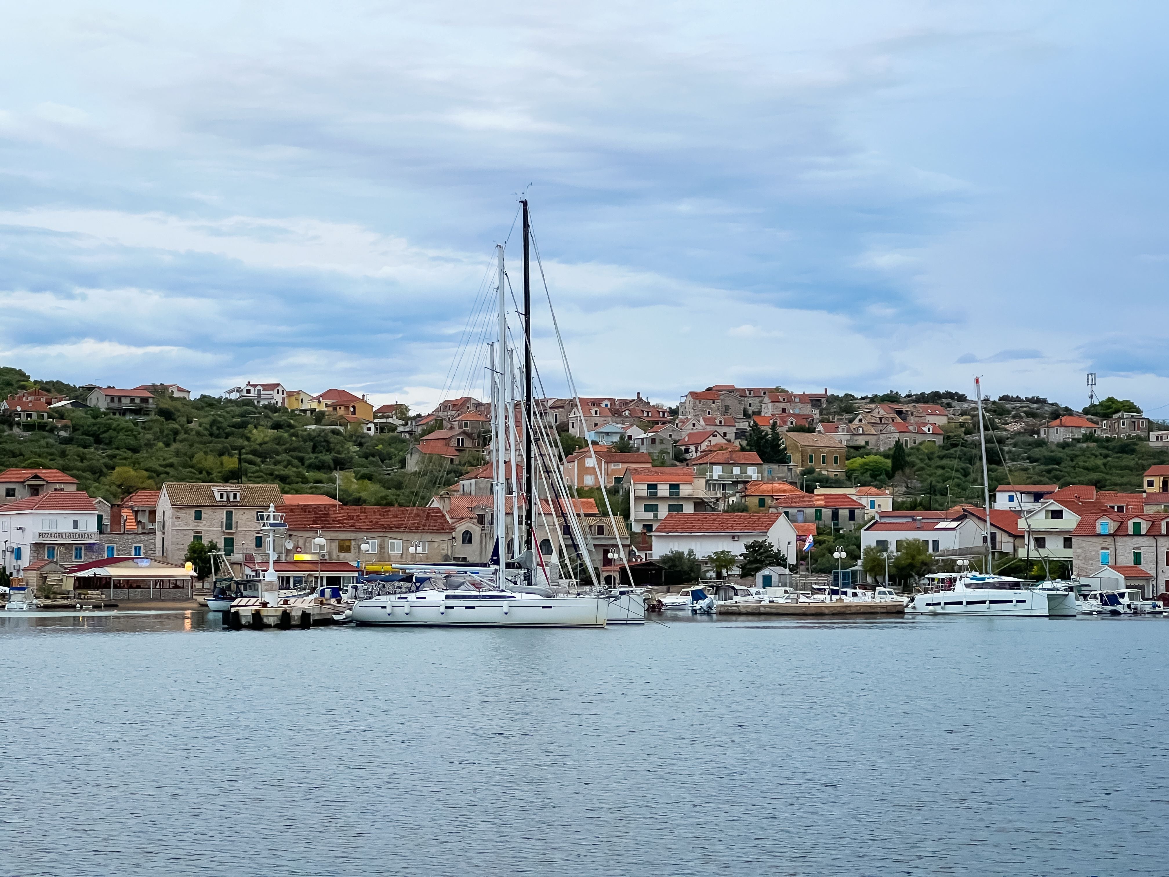 Segelboote liegen am Pier vor dem Ort Kaprije auf der Insel Kaprije in Dalmatien, Kroatien.