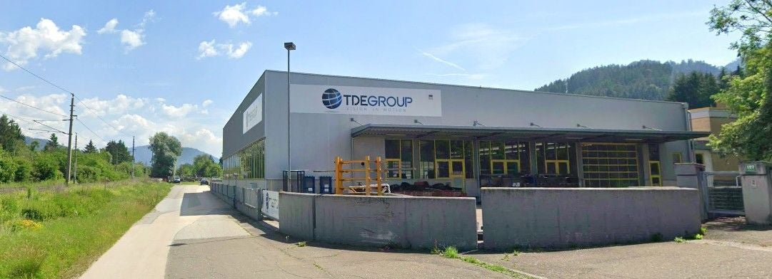 Industriegebäude der TDE Group mit Lagerbereich und Bergen im Hintergrund in Niklasdorf.