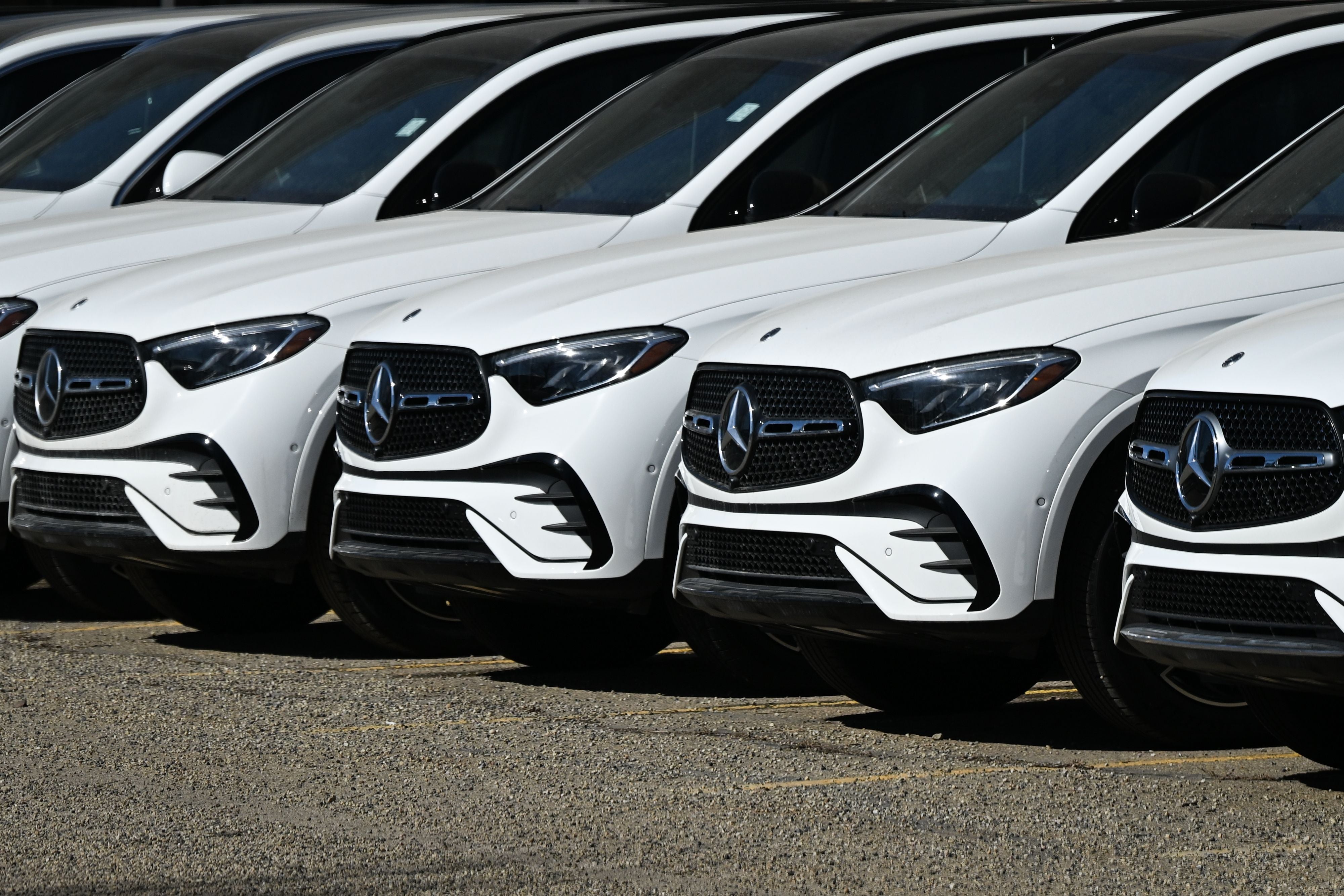 Mehrere weiße Mercedes-Benz Autos stehen nebeneinander auf einem Parkplatz.