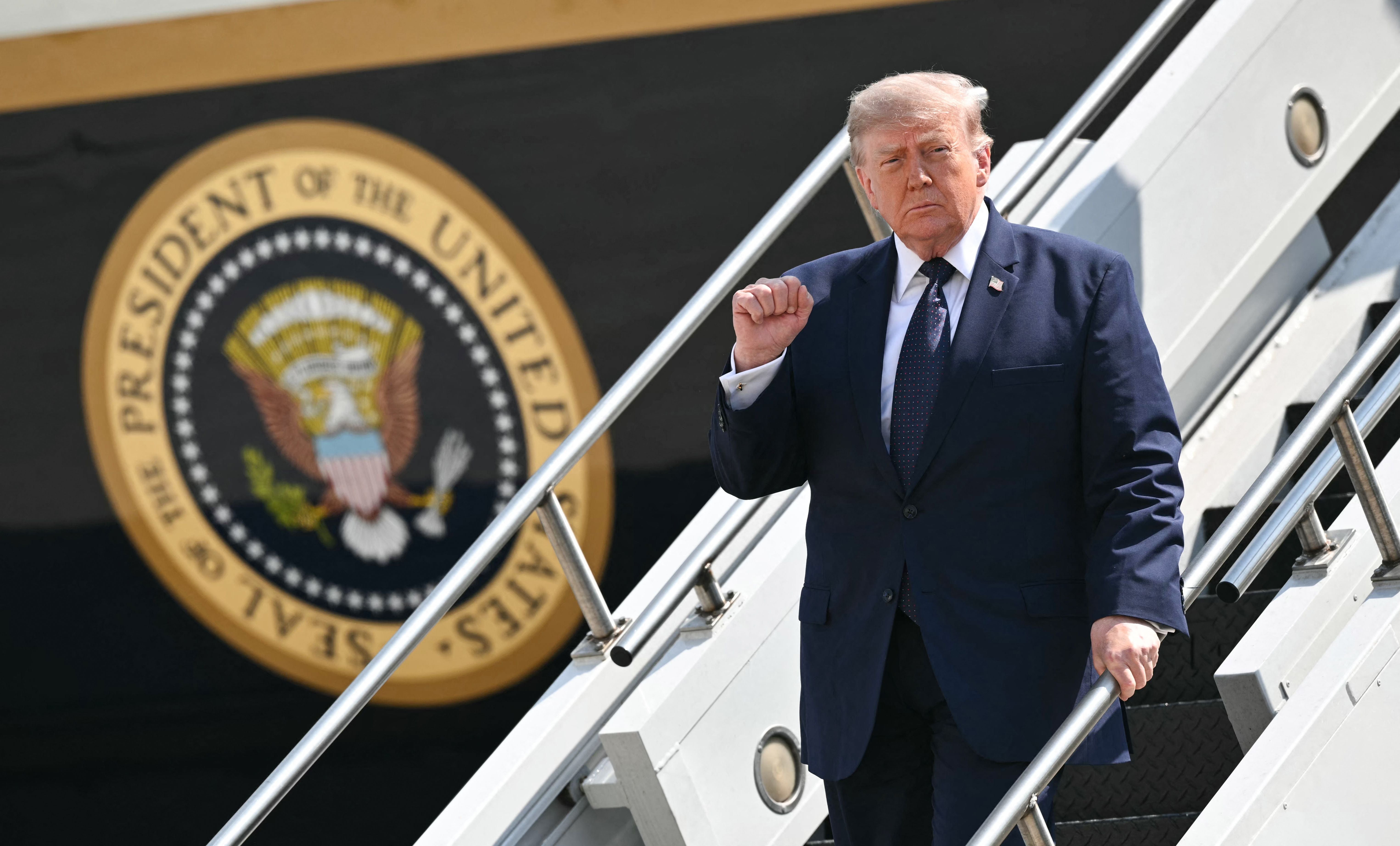Ein Mann im Anzug steigt die Treppe von Air Force One hinab, im Hintergrund das Präsidentensiegel.