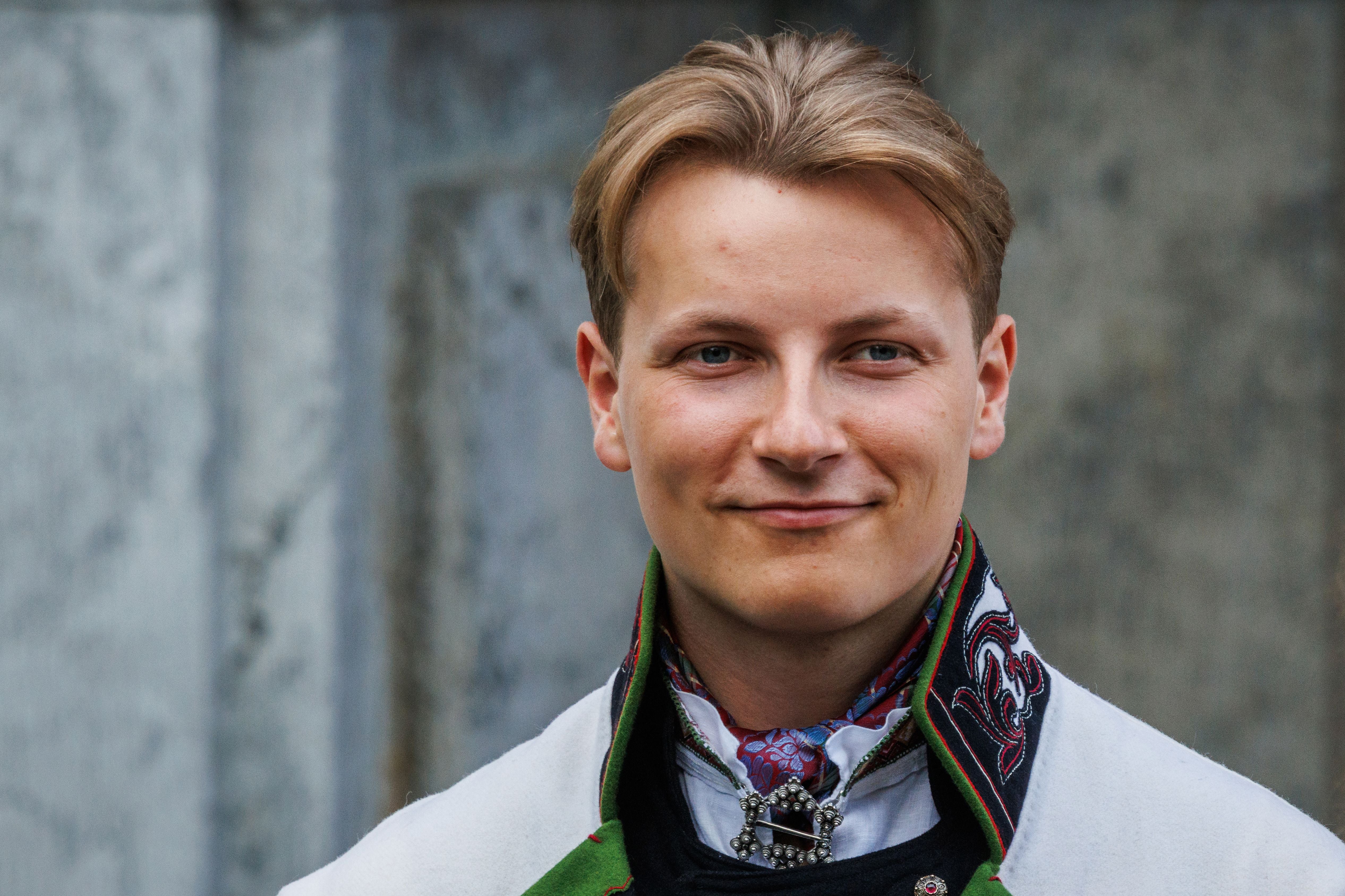 Ein junger Mann in traditioneller norwegischer Tracht lächelt in die Kamera.