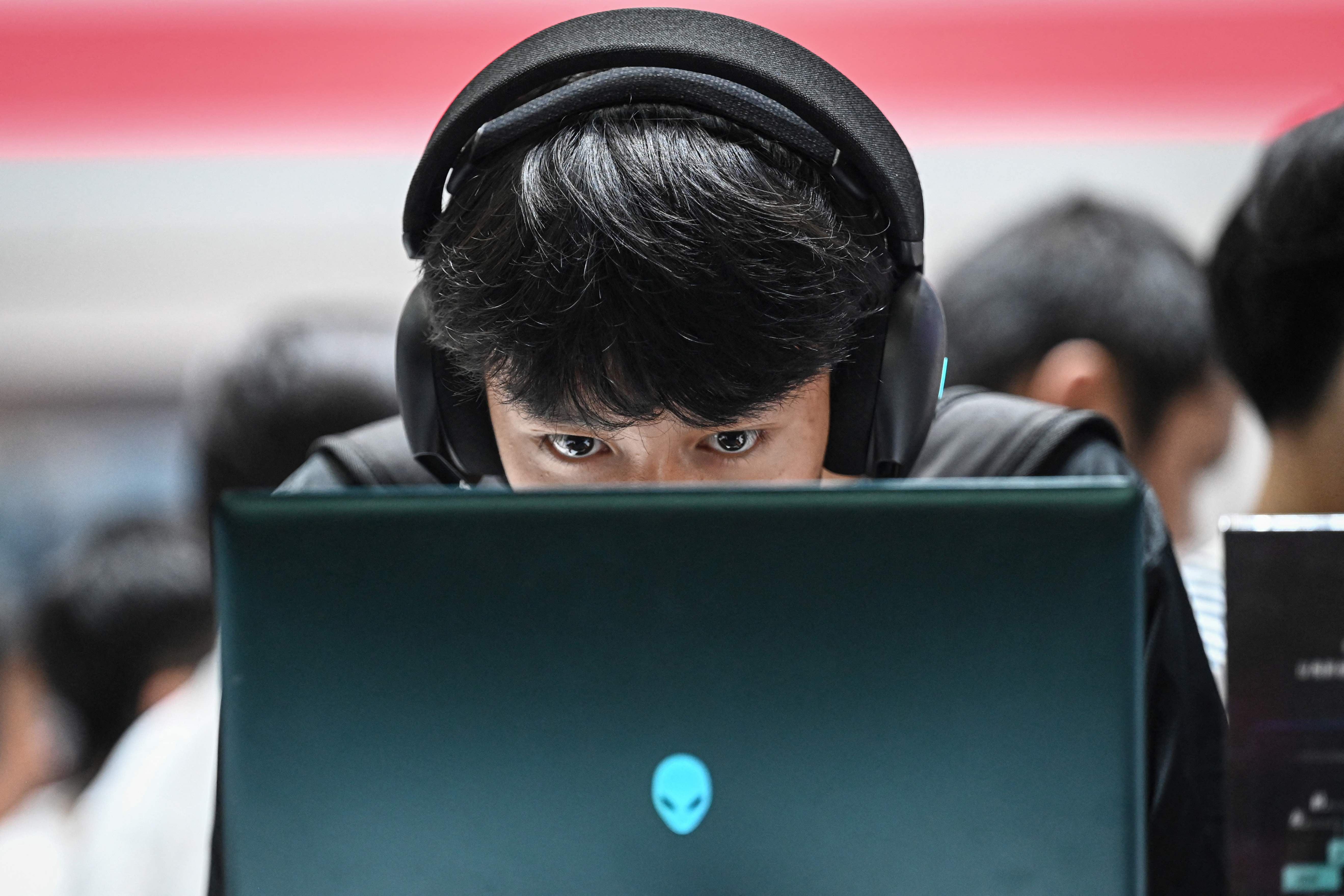 Mann mit Kopfhörern spielt konzentriert an einem Laptop auf einer Messe in Shanghai.
