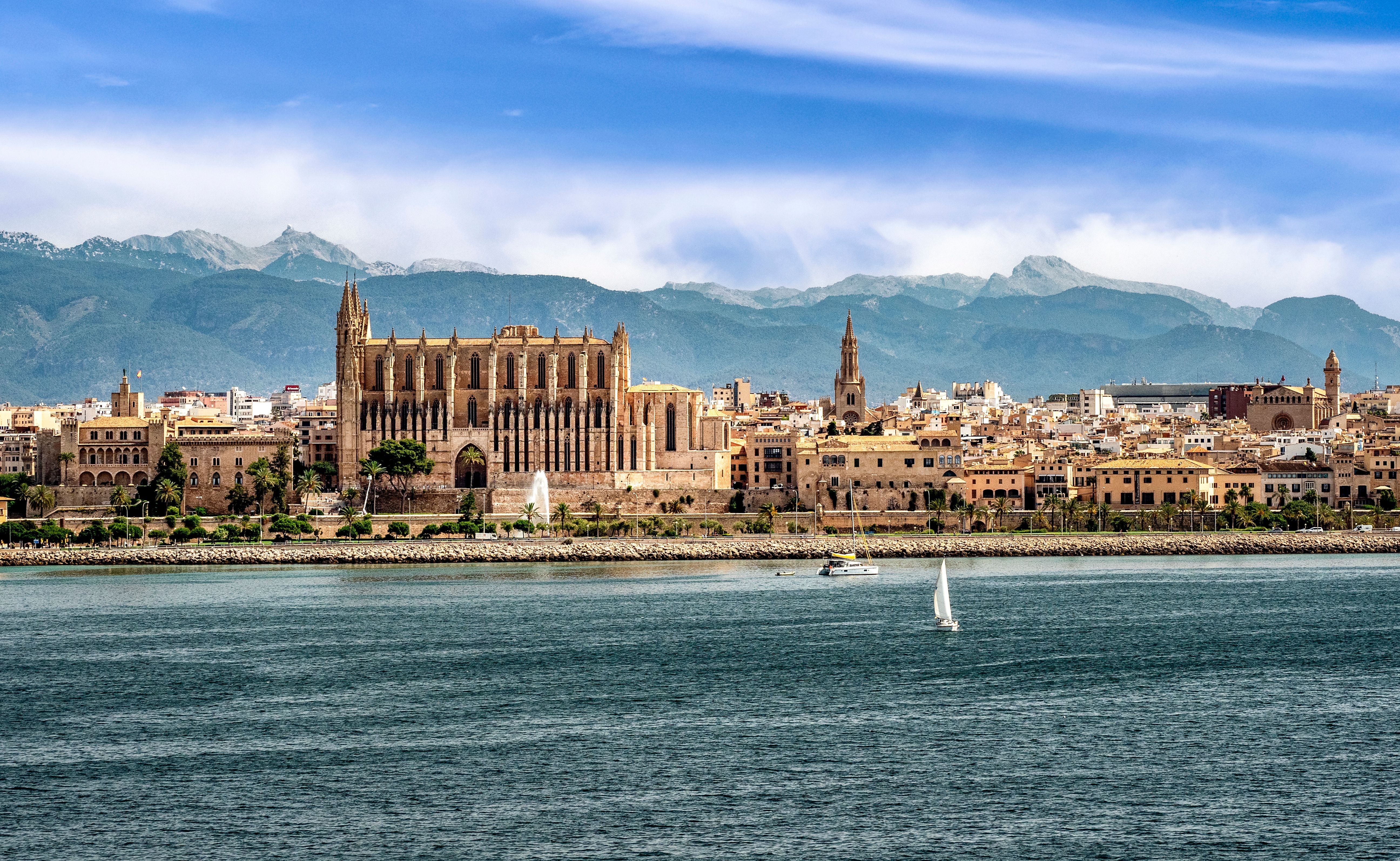 Blick auf Palma de Mallorca mit der Kathedrale im Vordergrund und Bergen im Hintergrund.
