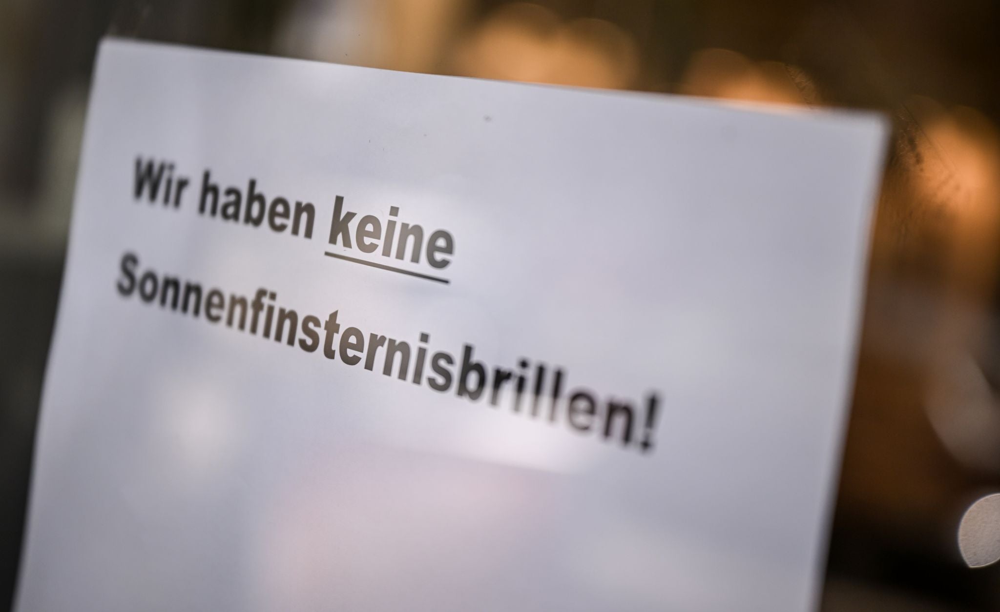 Berlin: An der Tür eines Optikergeschäfts steht ein Schild mit der Aufschrift "Wir haben keine Sonnenfinsternisbrillen!".