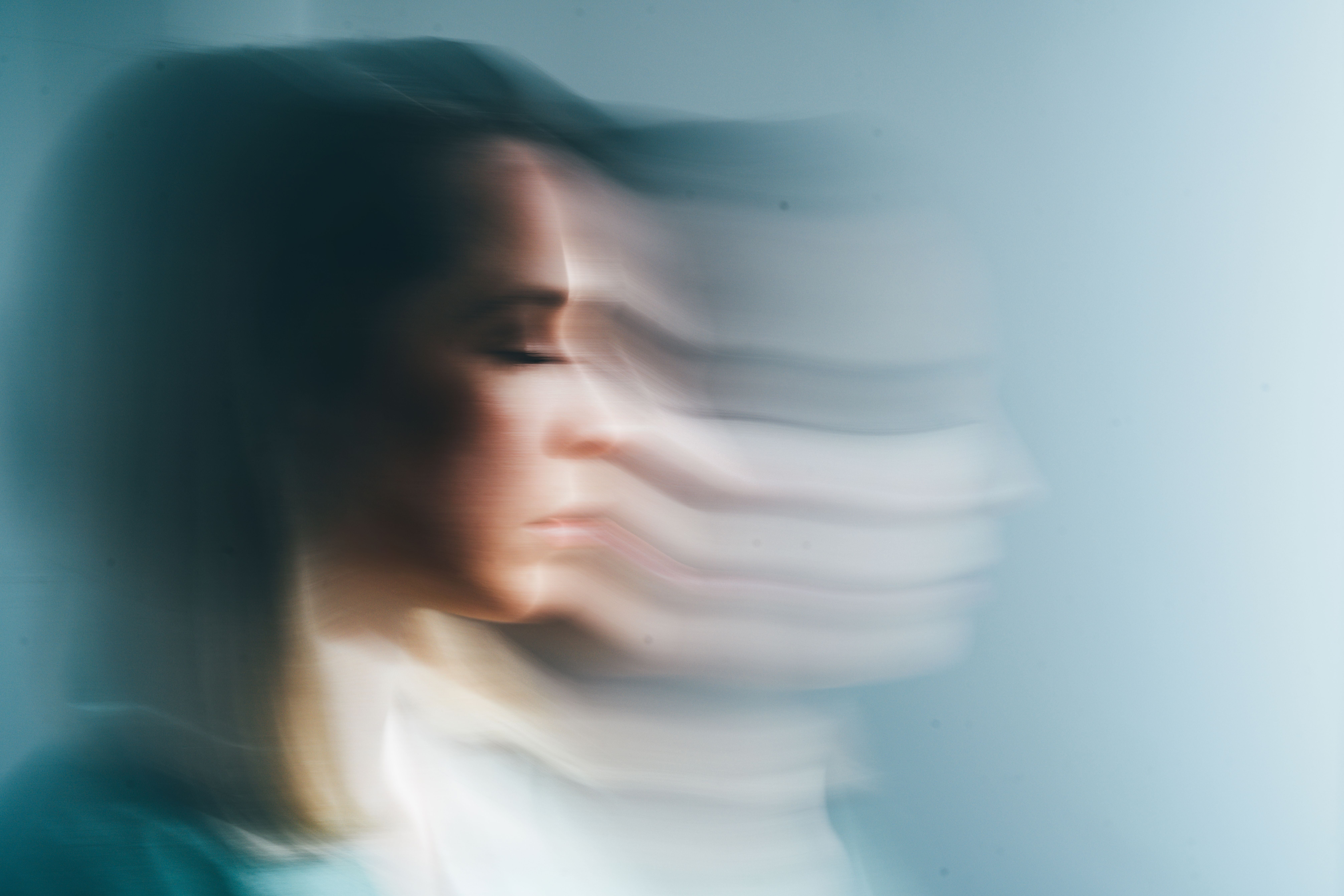 Verschwommene Profilaufnahme einer Frau mit geschlossenen Augen, mehrfach horizontal verzogen.