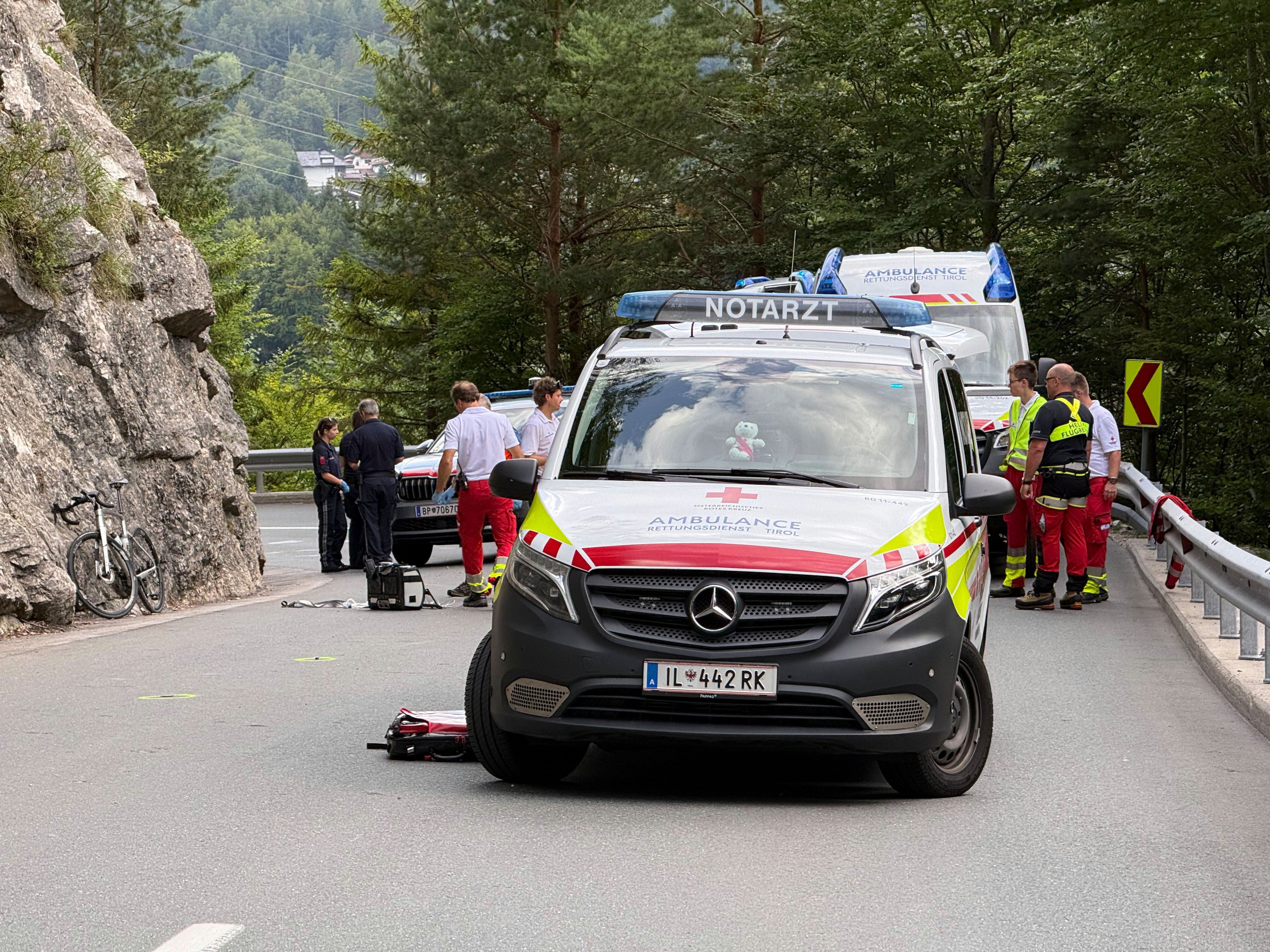 Unfallstelle mit Rettungsfahrzeugen, Sanitätern und einem am Straßenrand liegenden Fahrrad.