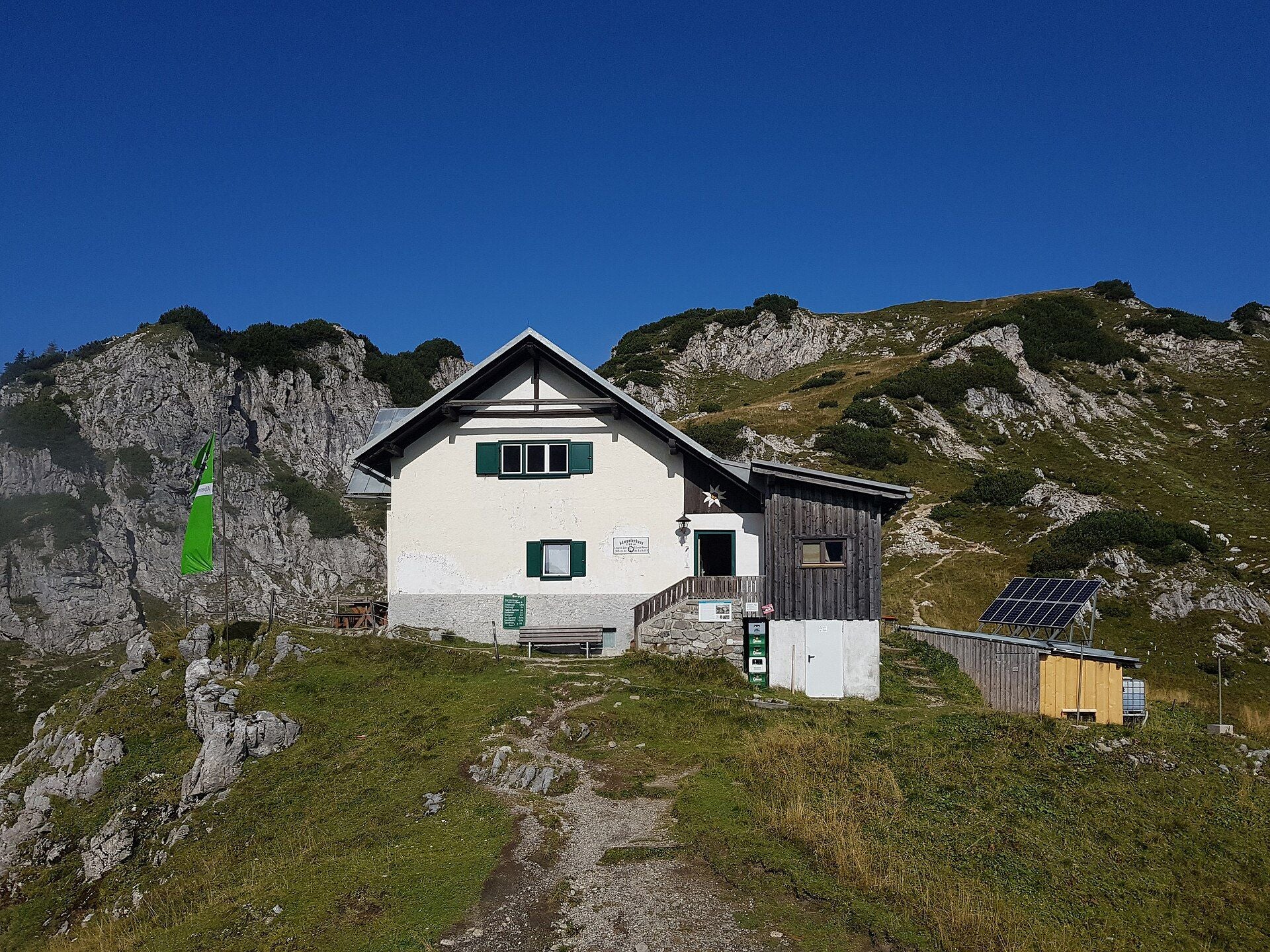 Berghütte Admonter Haus vor felsiger Berglandschaft und blauem Himmel bei Sonnenschein.