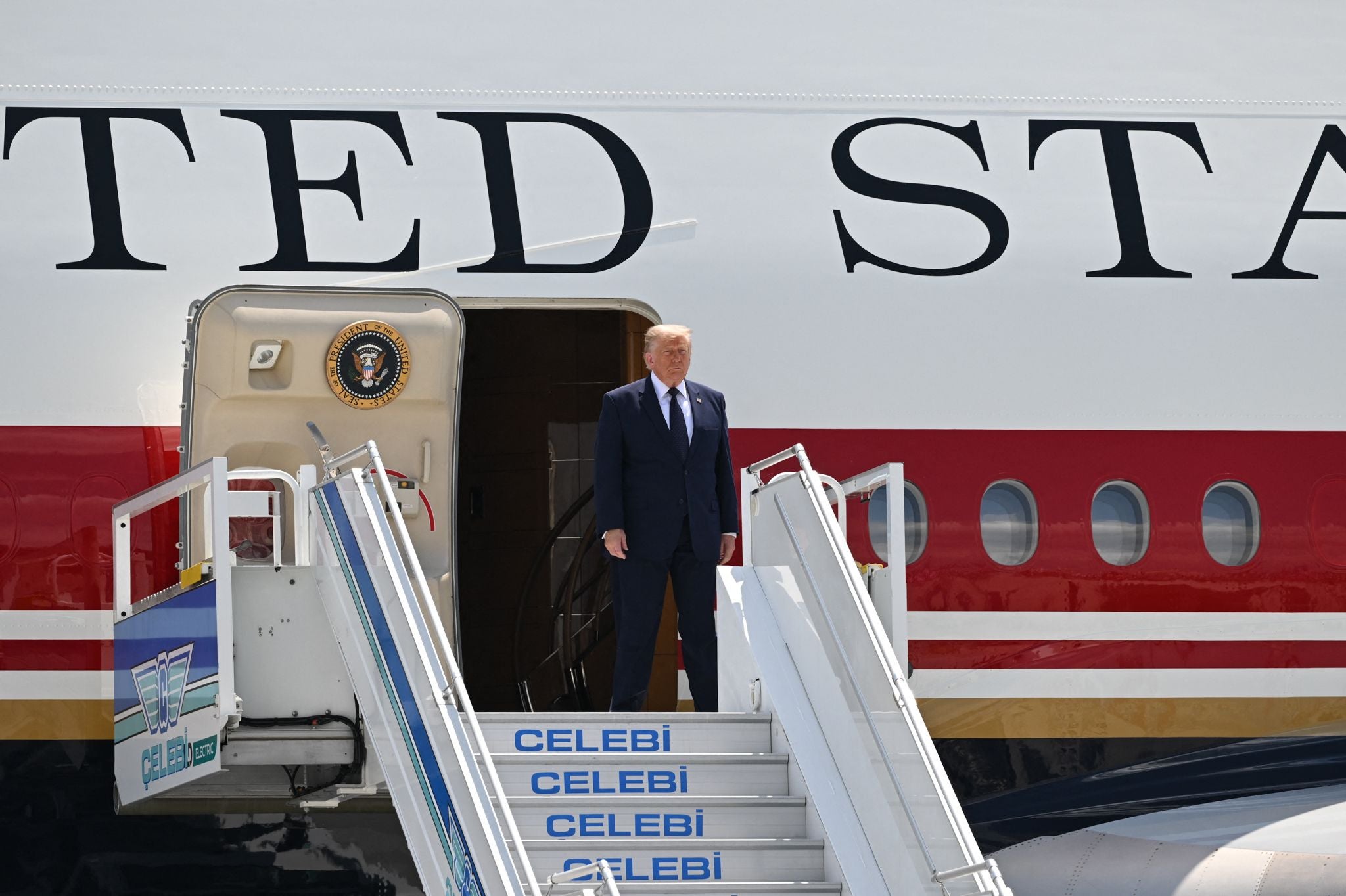 Ein Mann im Anzug steigt aus einem Flugzeug mit der Aufschrift „UNITED STATES“ aus.