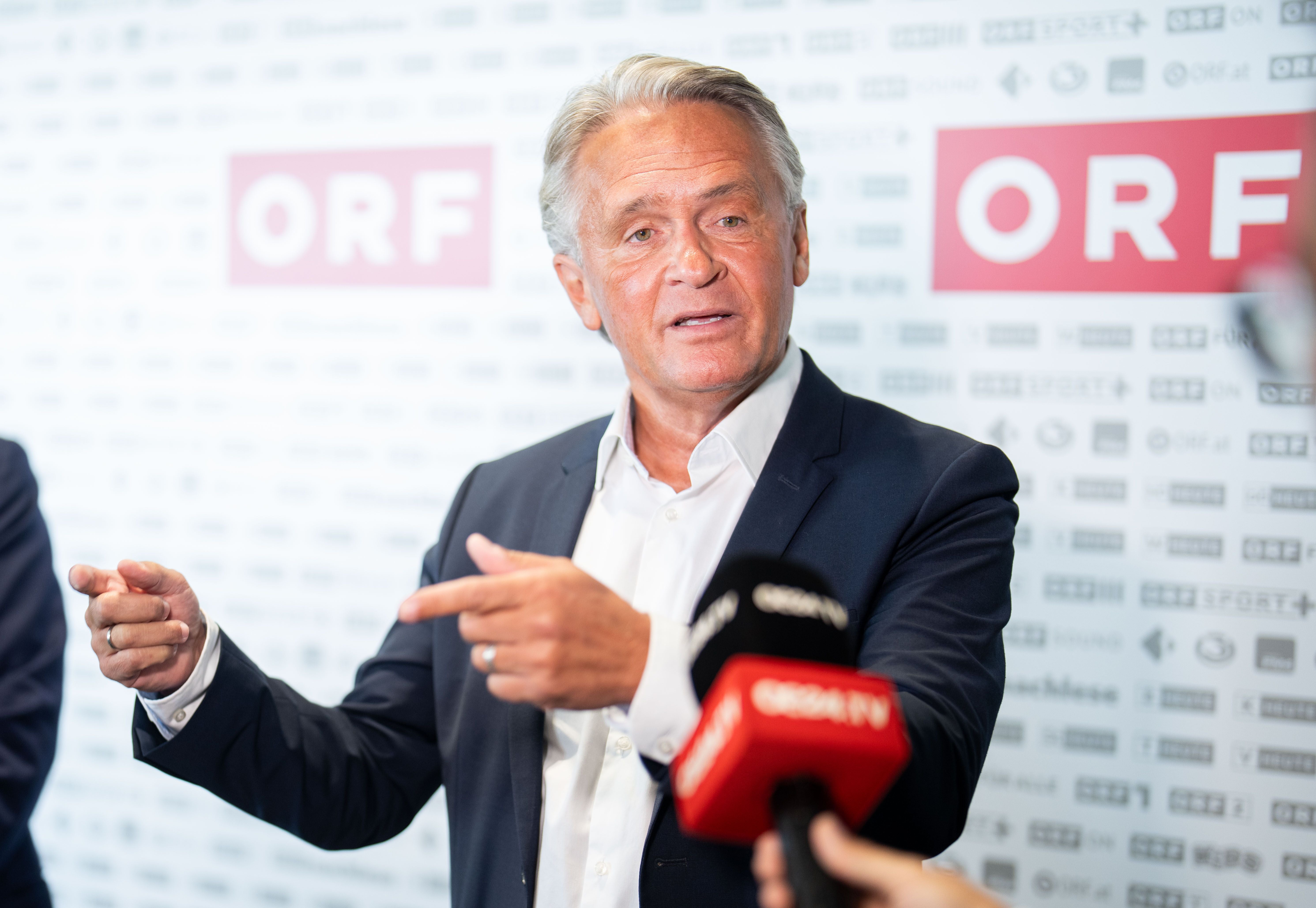 Ein Mann im Anzug spricht vor ORF-Logos in Mikrofone bei einer Pressekonferenz.