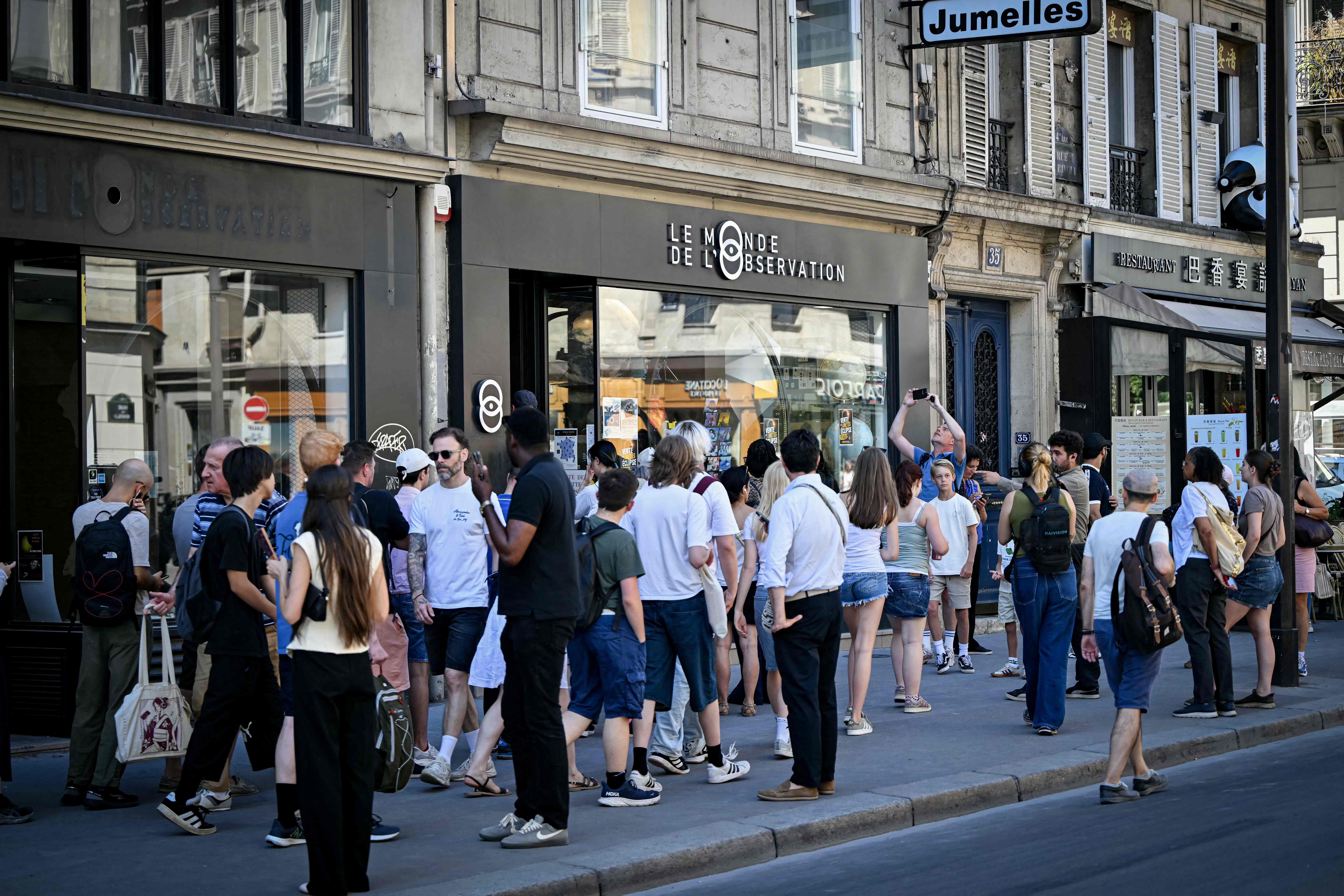 Kunden stehen in Paris vor einem auf Funktionaloptometrie spezialisierten Optikergeschäft Schlange, um Sonnenfinsternisbrillen zu kaufen. In Frankreich wird die Sonnenfinsternis am 12. August nur partiell zu sehen sein, dennoch ist die Nachfrage nach den speziellen Brillen sprunghaft angestiegen. In Paris waren einige Apotheken bereits ausverkauft, während andere noch Bestände hatten, da Kunden herbeieilten, um sich noch rechtzeitig ein Exemplar zu sichern.