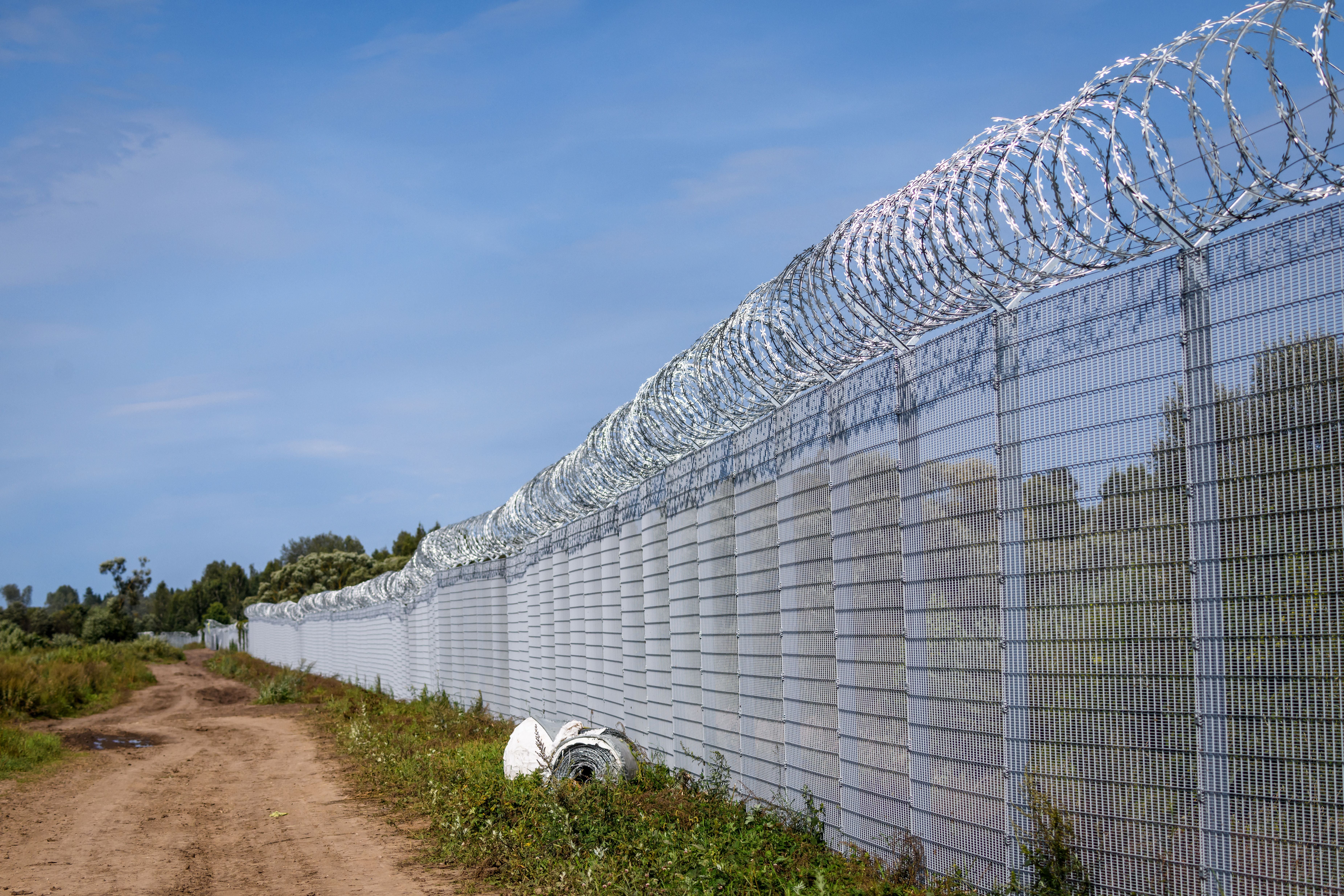 Hoher Grenzzaun mit Stacheldraht an einer Landstraße bei Karsava, Lettland.