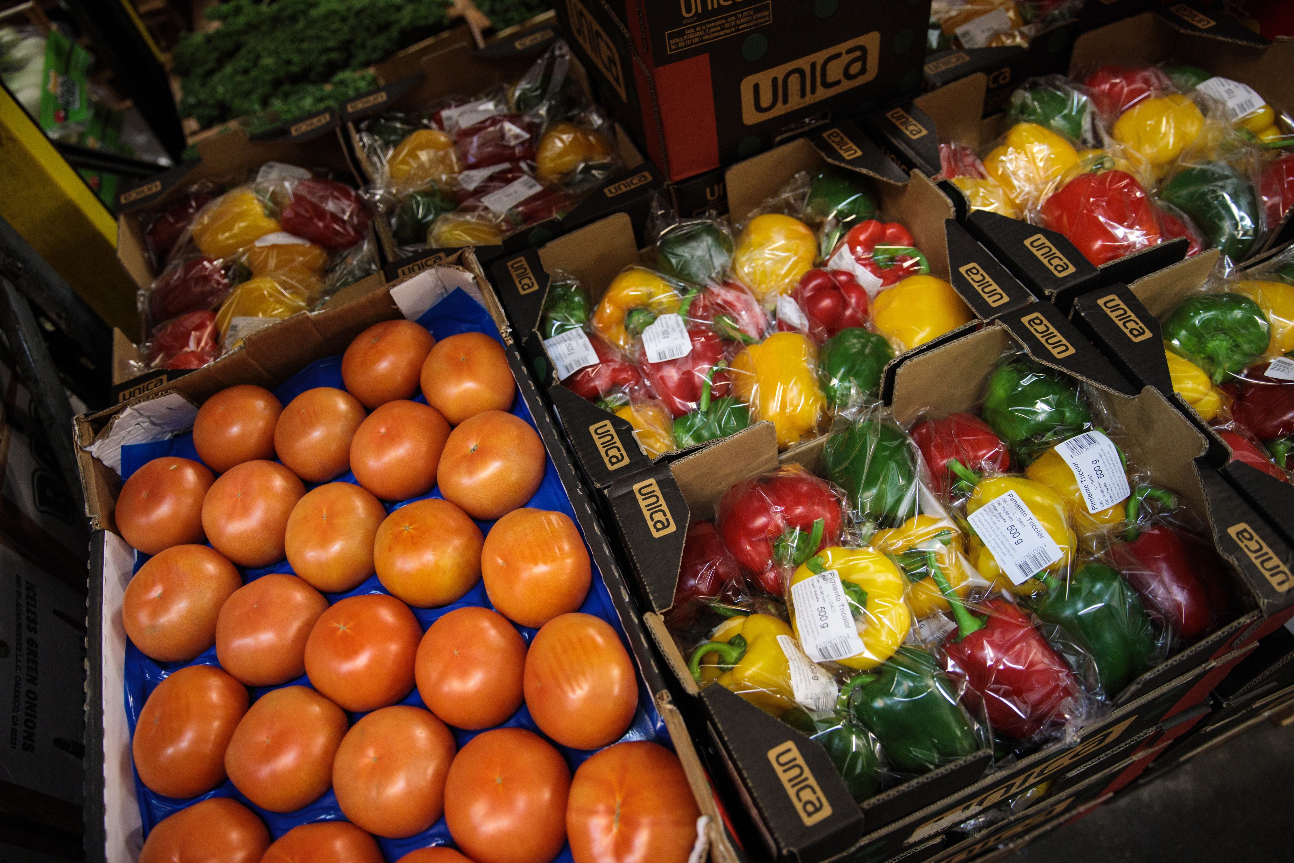 Kisten mit Tomaten und verpackten Paprika in einem Großhandelsmarkt für Obst und Gemüse.