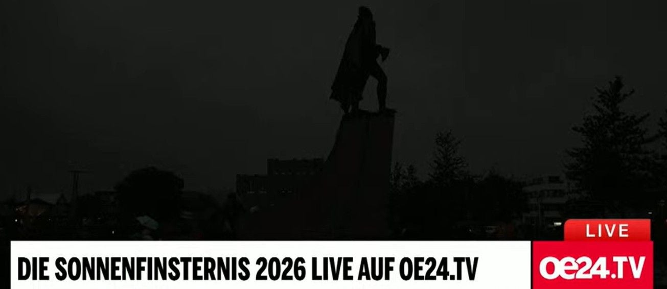 Eine Sonnenfinsternis verdunkelt Reykjavík mit einer Statue im Vordergrund.