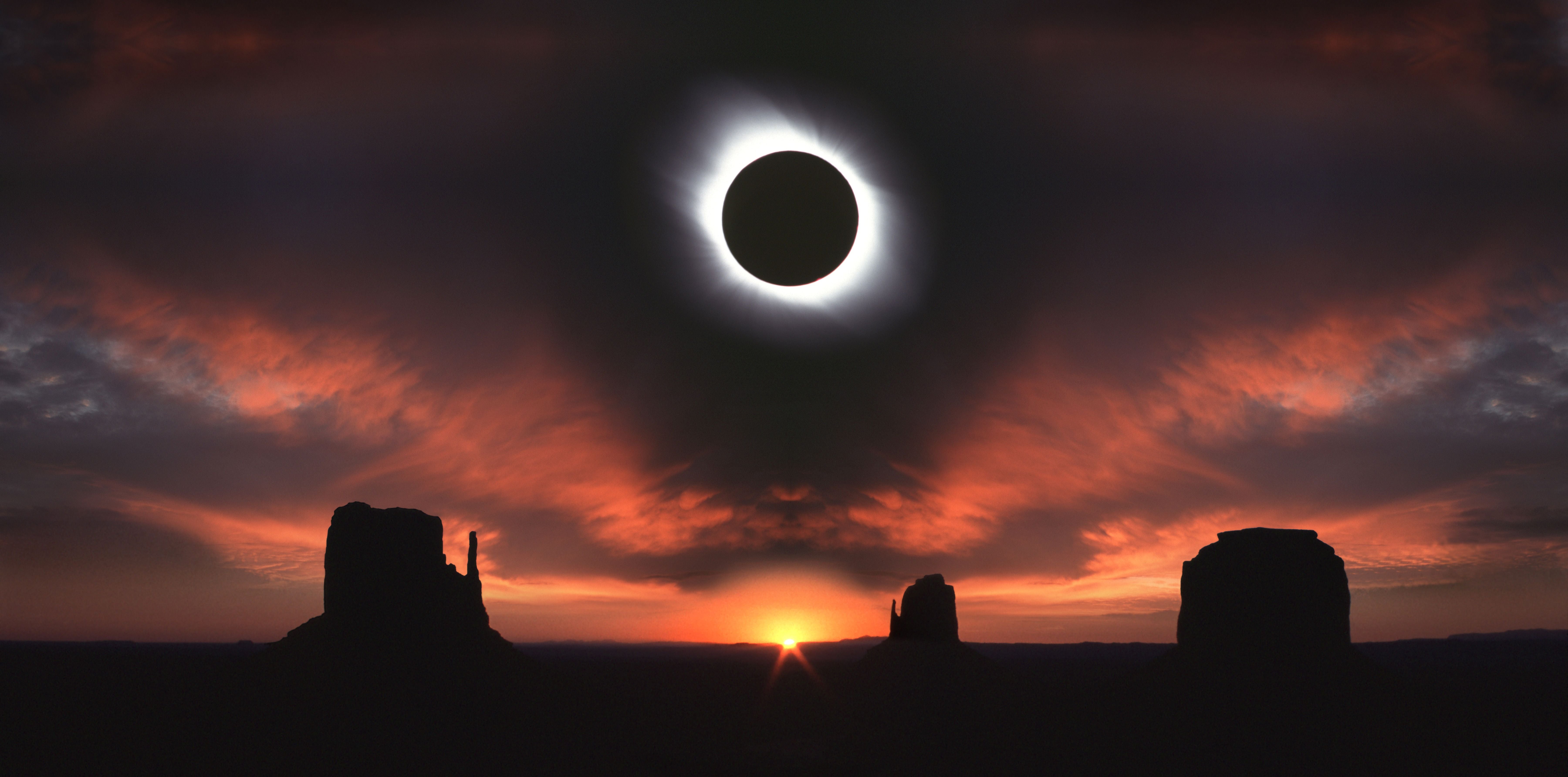 Totale Sonnenfinsternis über dem Monument Valley bei Sonnenaufgang und farbigem Himmel.