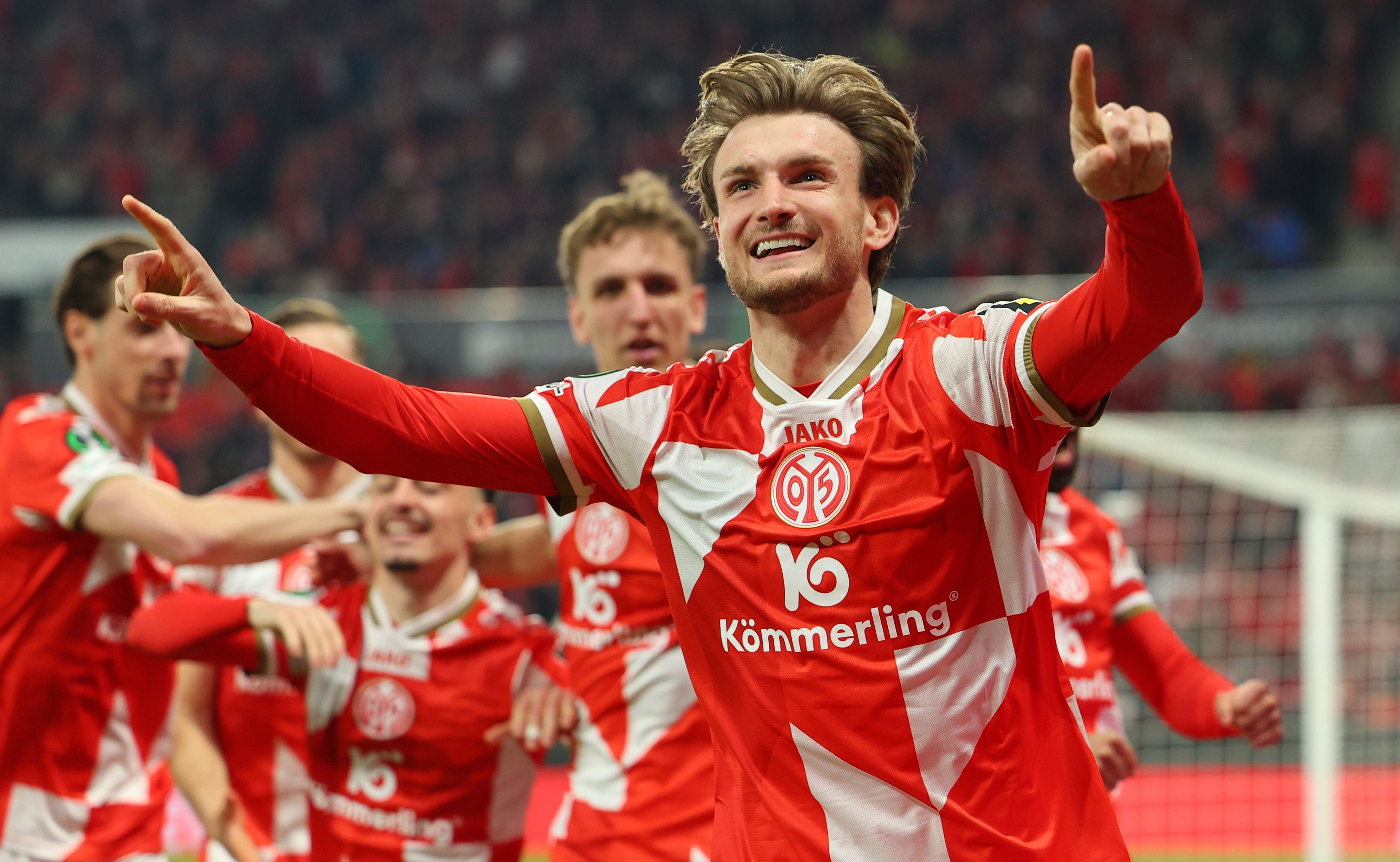 Ein Fußballspieler von Mainz 05 jubelt mit ausgestreckten Armen auf dem Spielfeld.