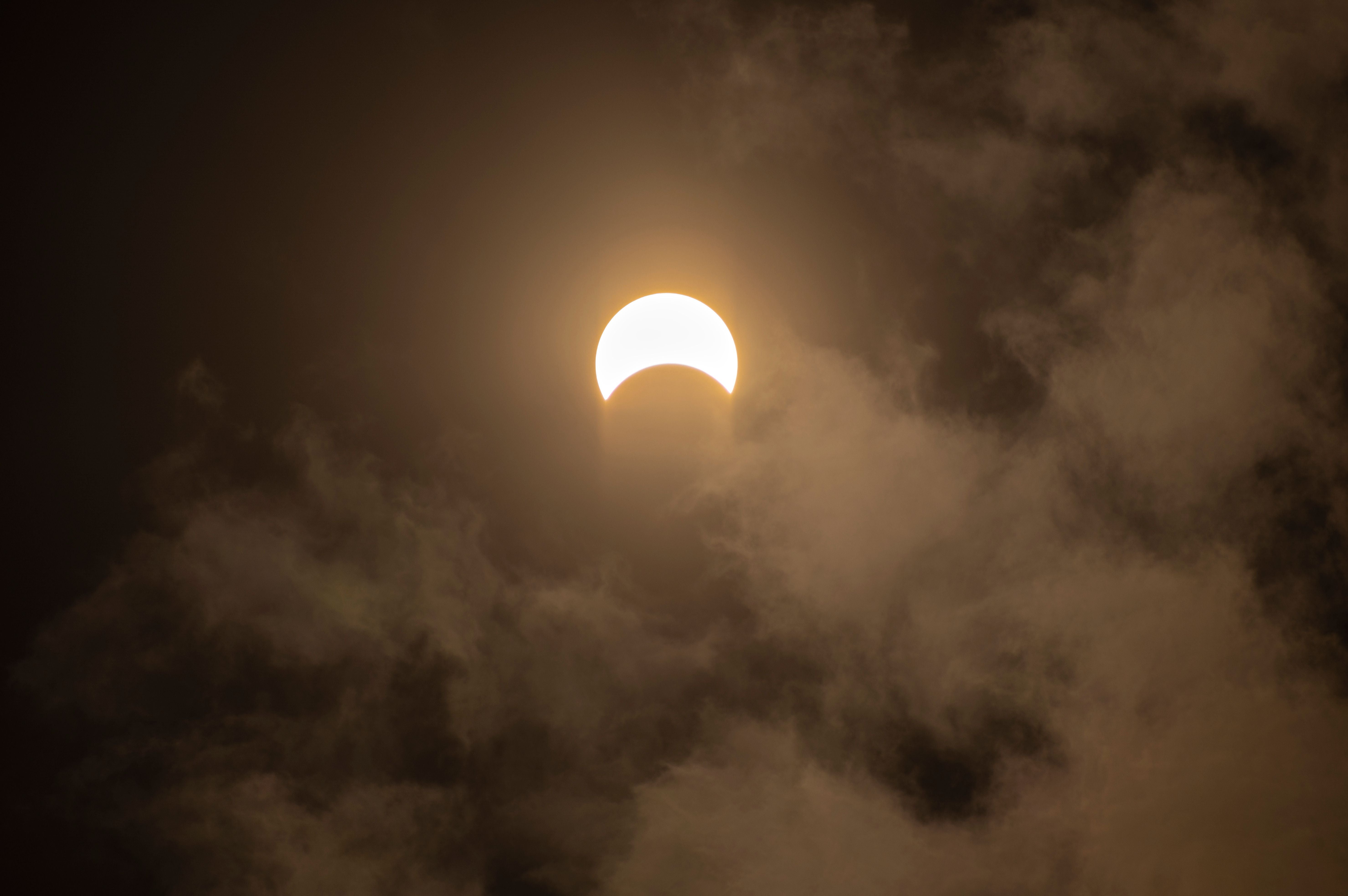 Partielle Sonnenfinsternis hinter Wolken am dunklen Himmel, aufgenommen in Herriman, Utah.