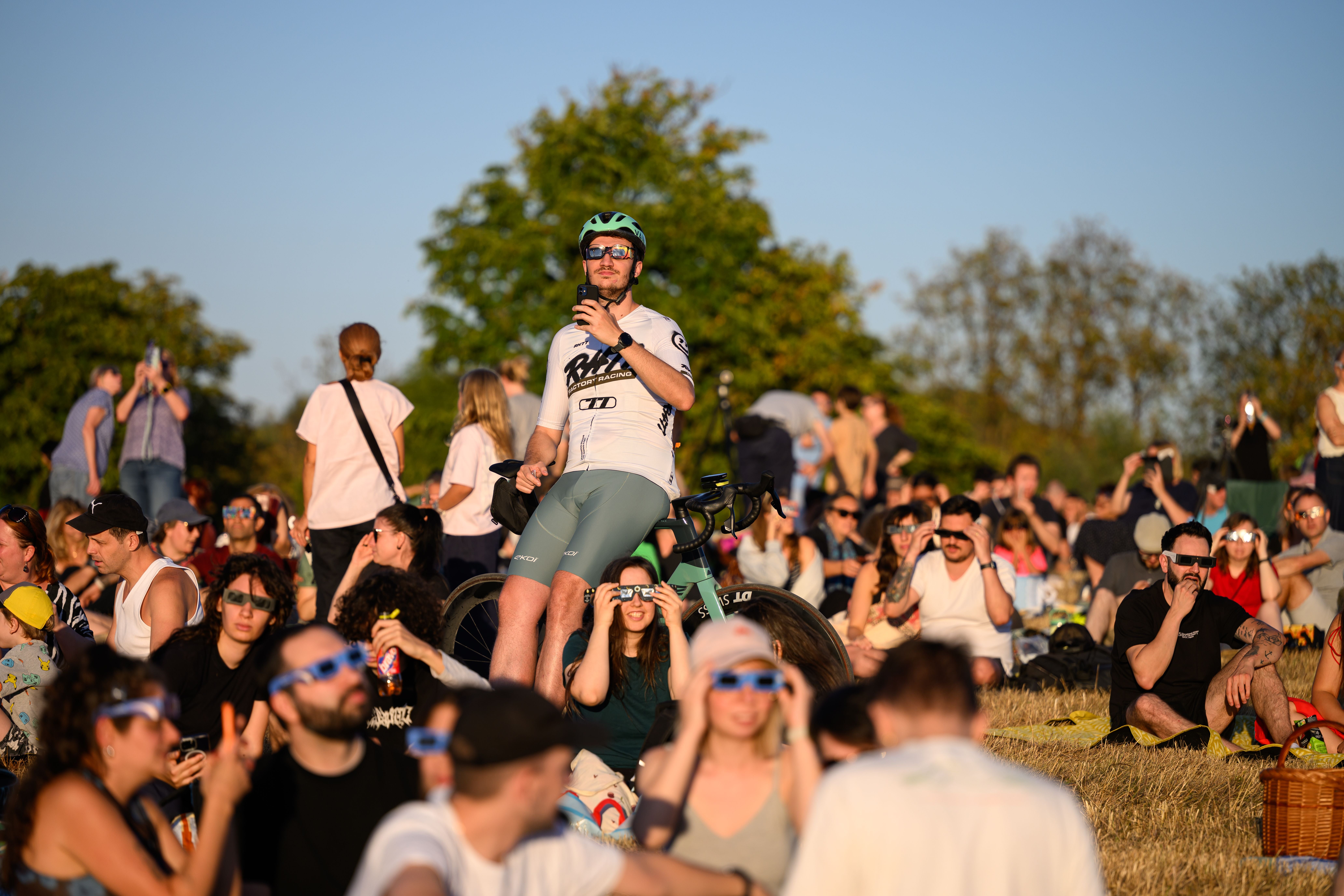 Viele Menschen mit Sonnenfinsternisbrillen beobachten eine partielle Sonnenfinsternis auf der Sophienalpe in Wien.