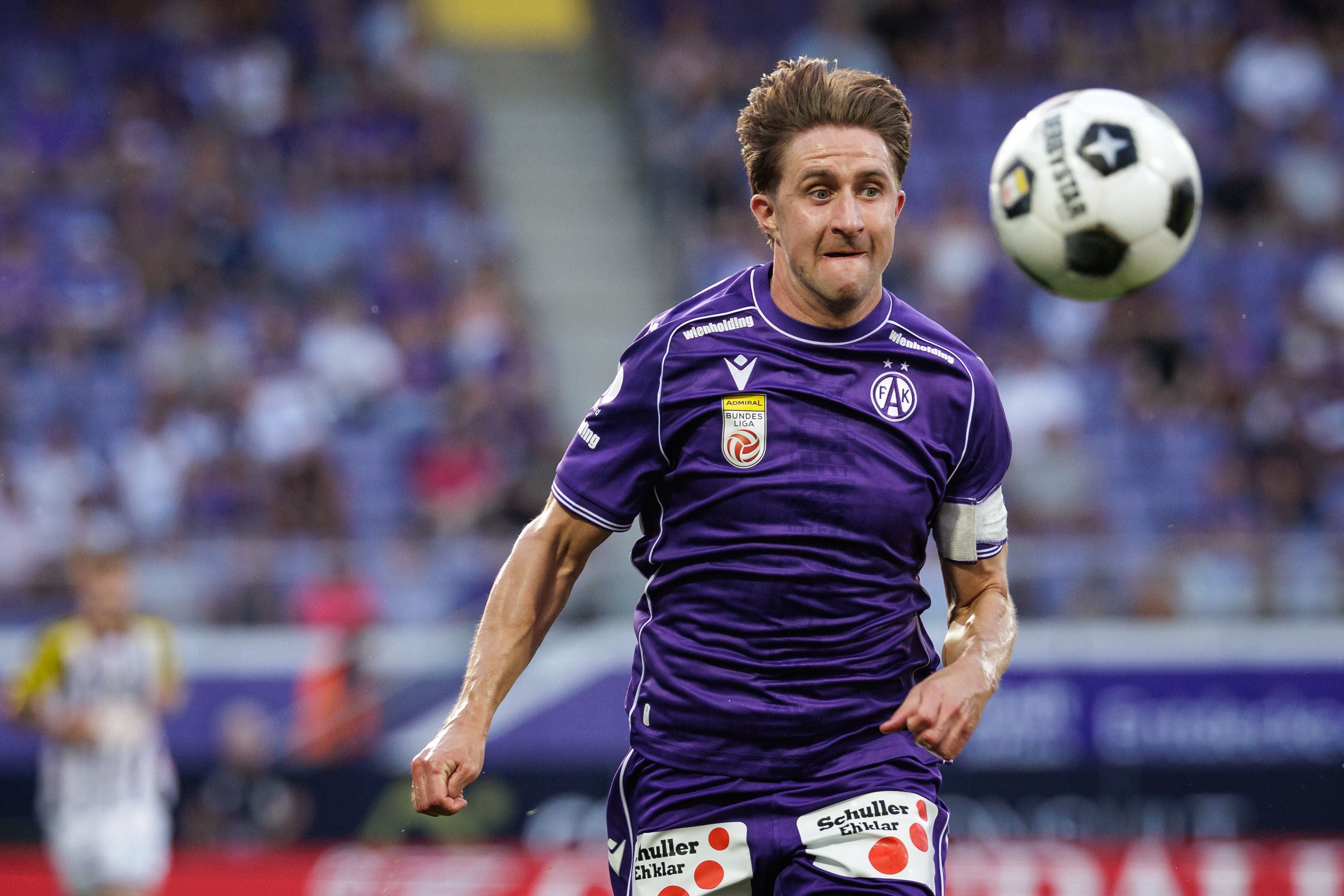 Ein Fußballspieler von Austria Wien läuft im Spiel, der Ball schwebt vor seinem Gesicht.