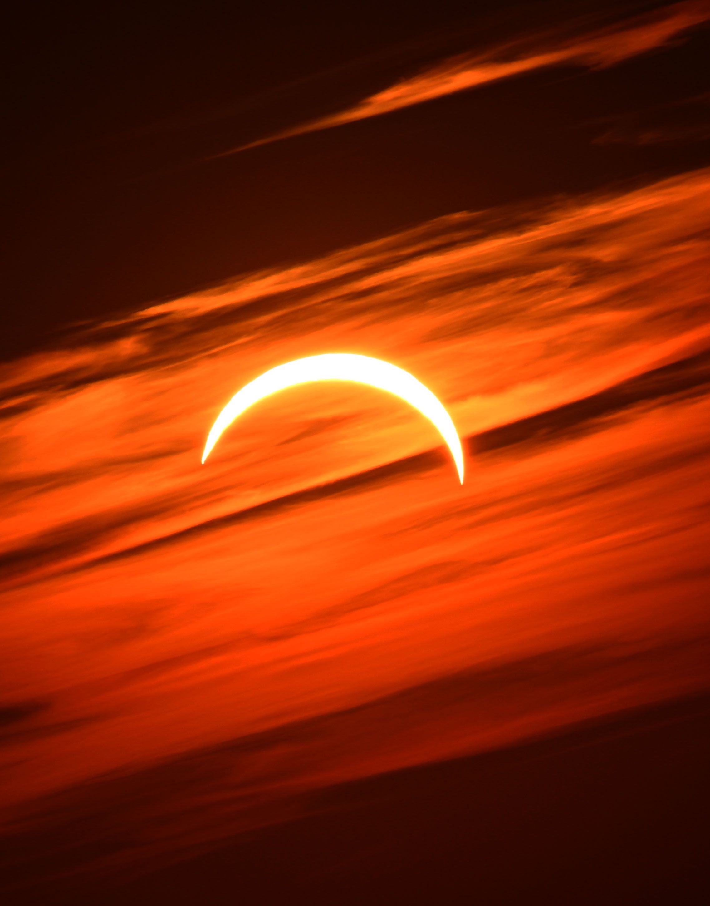 Partielle Sonnenfinsternis über Salzburg mit orangefarbenen Wolken am Himmel.