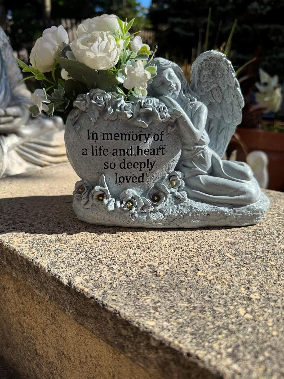 Engelsfigur mit Herz, Blumen und der Gravur: "In memory of a life and heart so deeply loved".