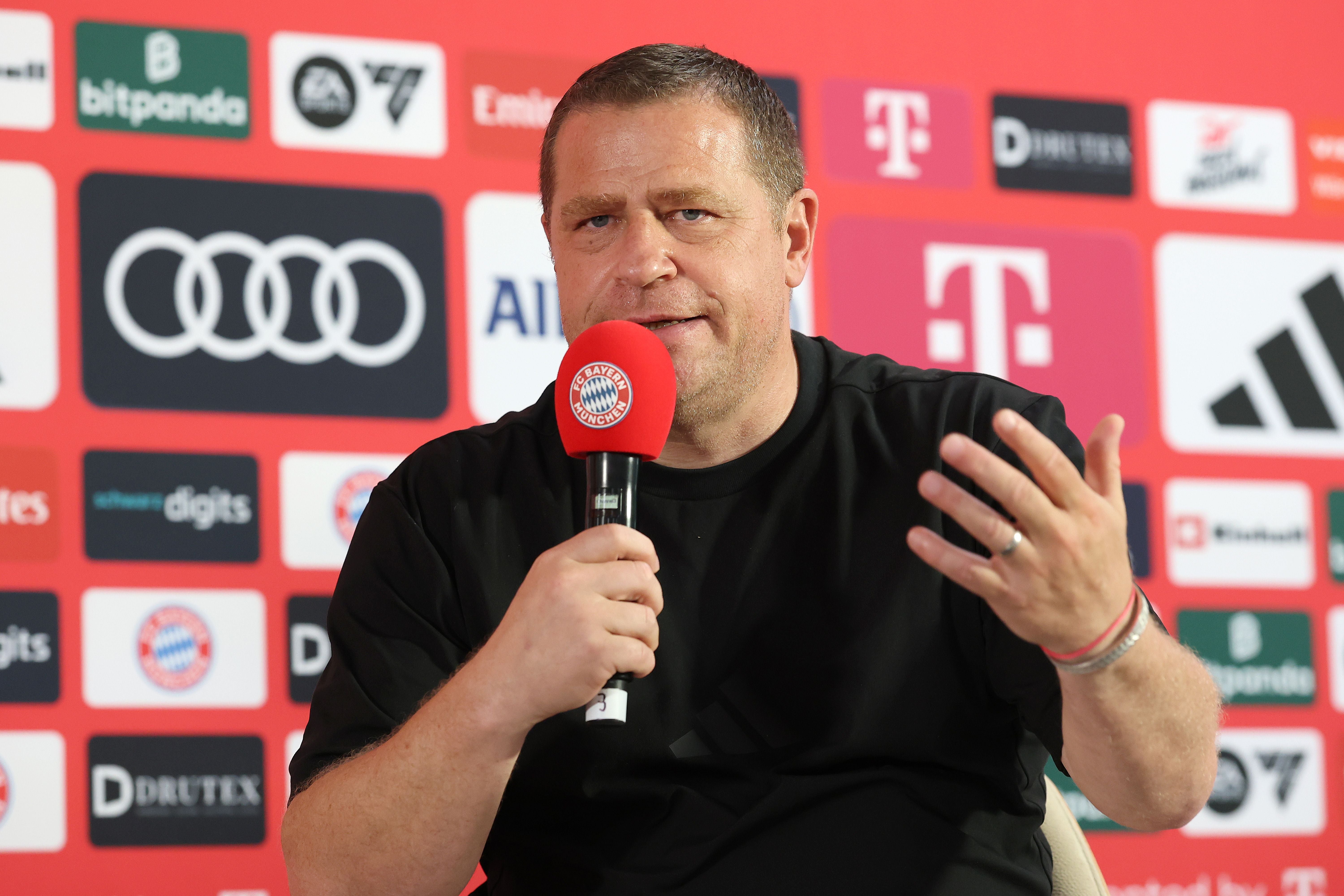 Max Eberl spricht auf einer Pressekonferenz mit rotem FC Bayern München Mikrofon.