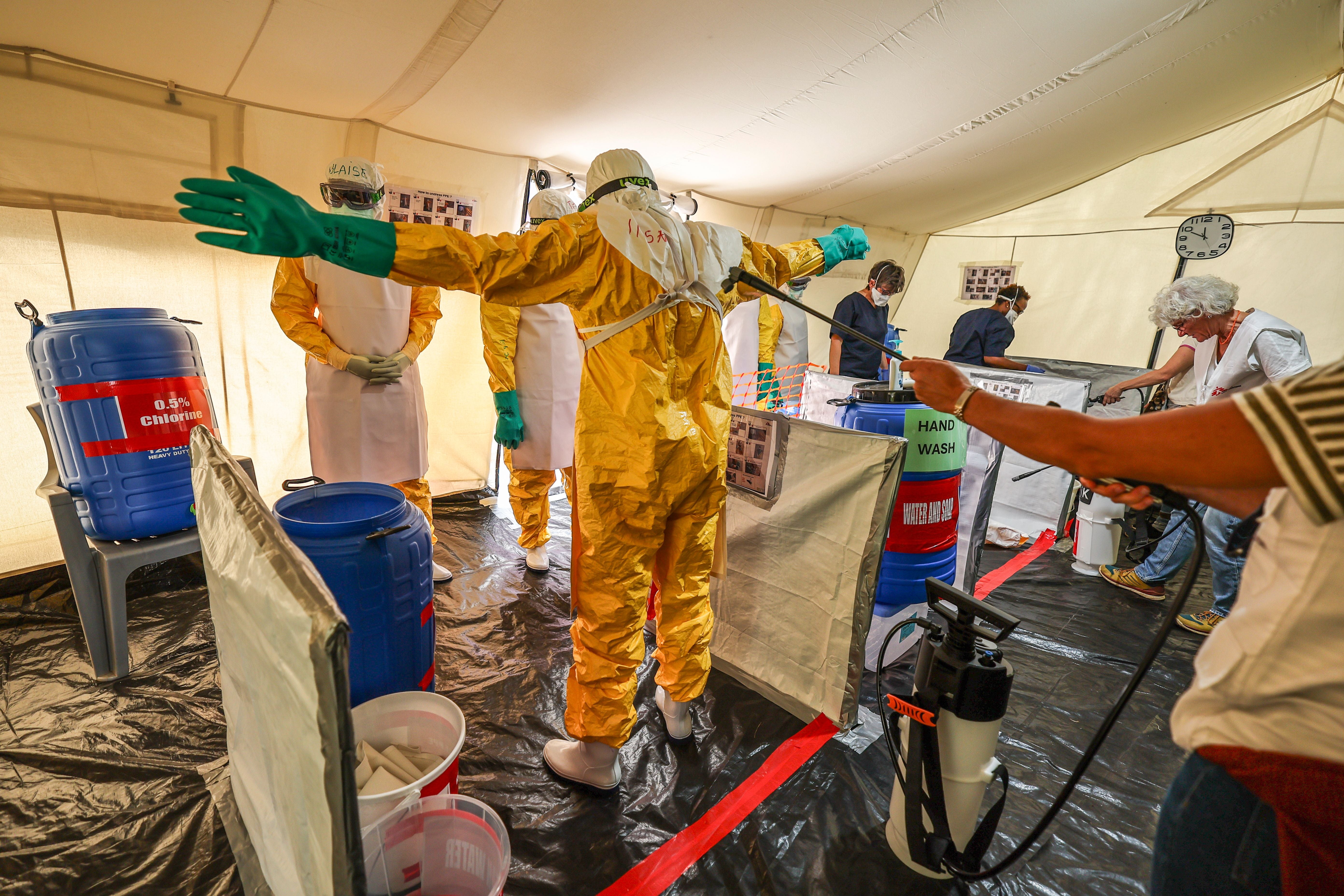 Freiwillige in Schutzanzügen üben Desinfektion bei Ebola-Training in einem Zelt.