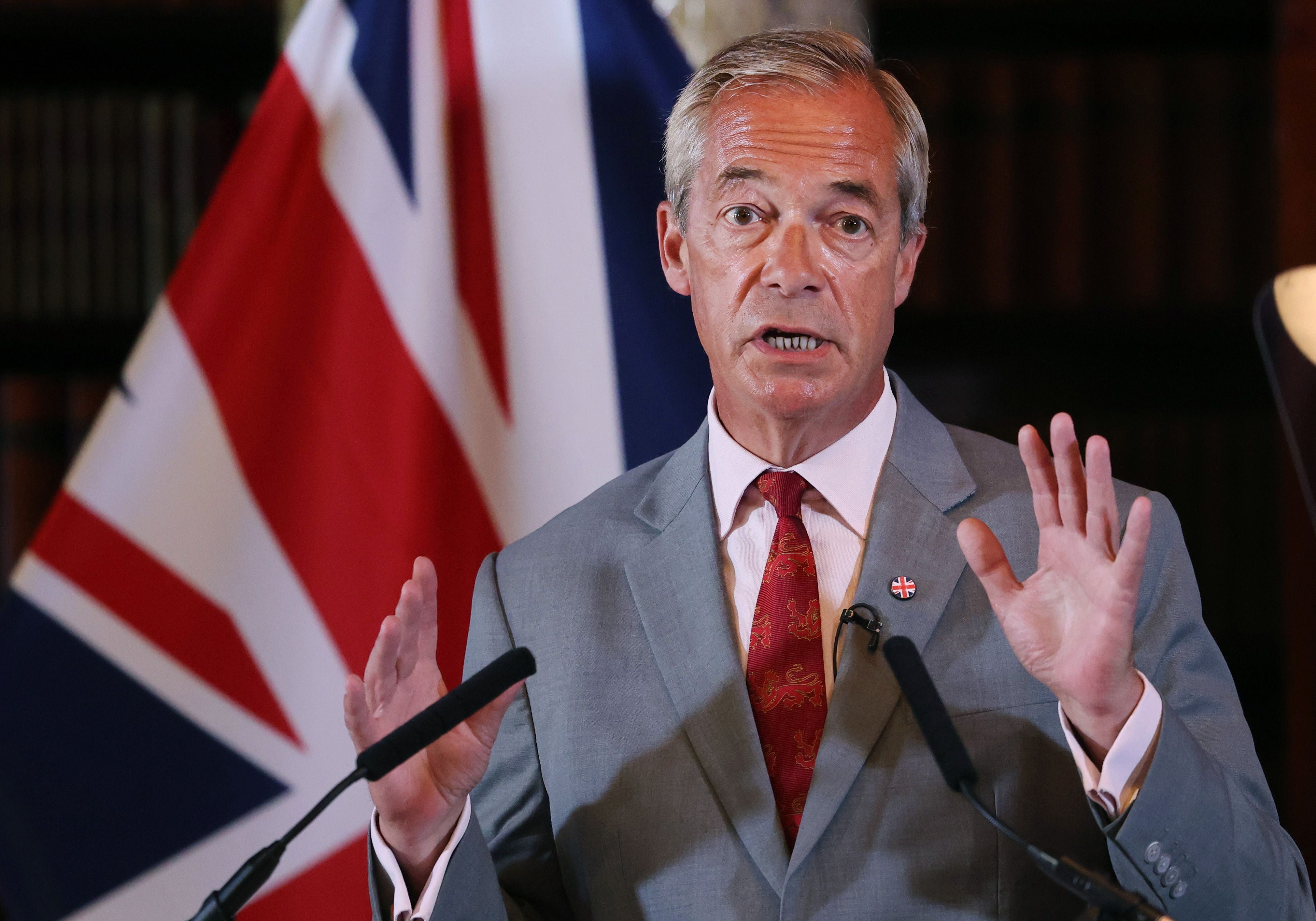Ein Mann im Anzug spricht bei einer Pressekonferenz vor einer britischen Flagge.