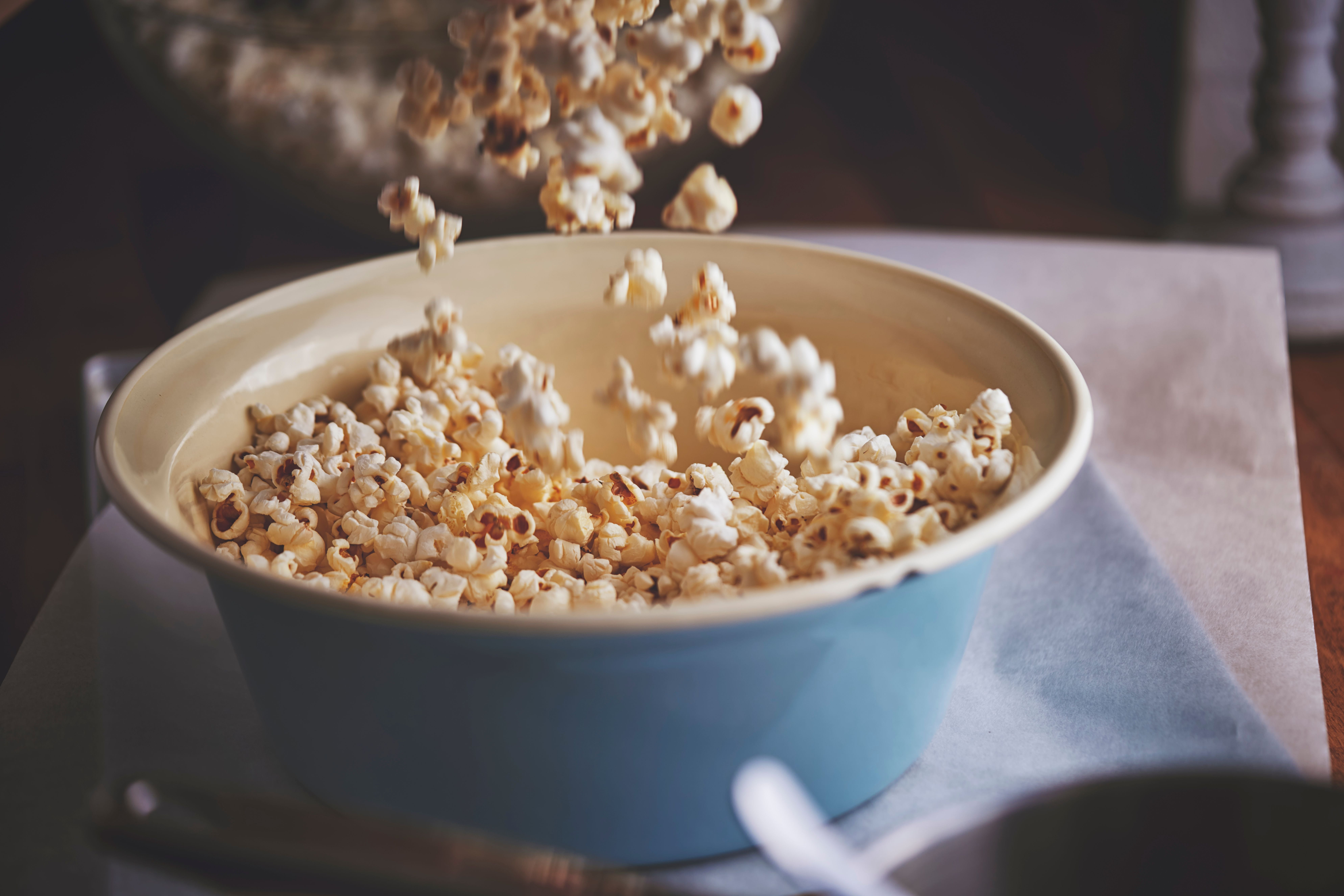 Frisch gemachtes Popcorn wird in eine große, blaue Schüssel gefüllt.