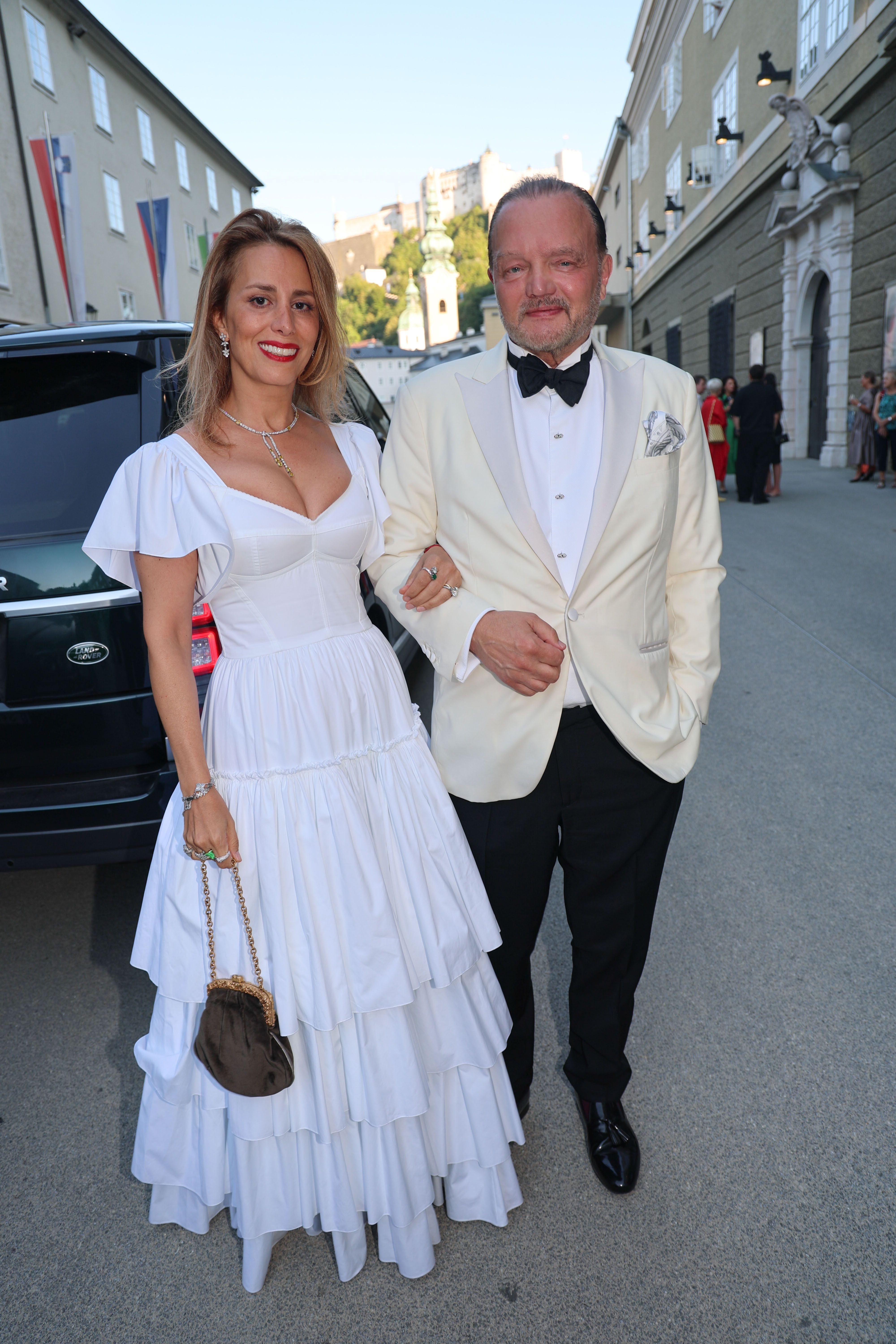 Ein Paar in eleganter Abendgarderobe steht vor einem Gebäude in Salzburg.