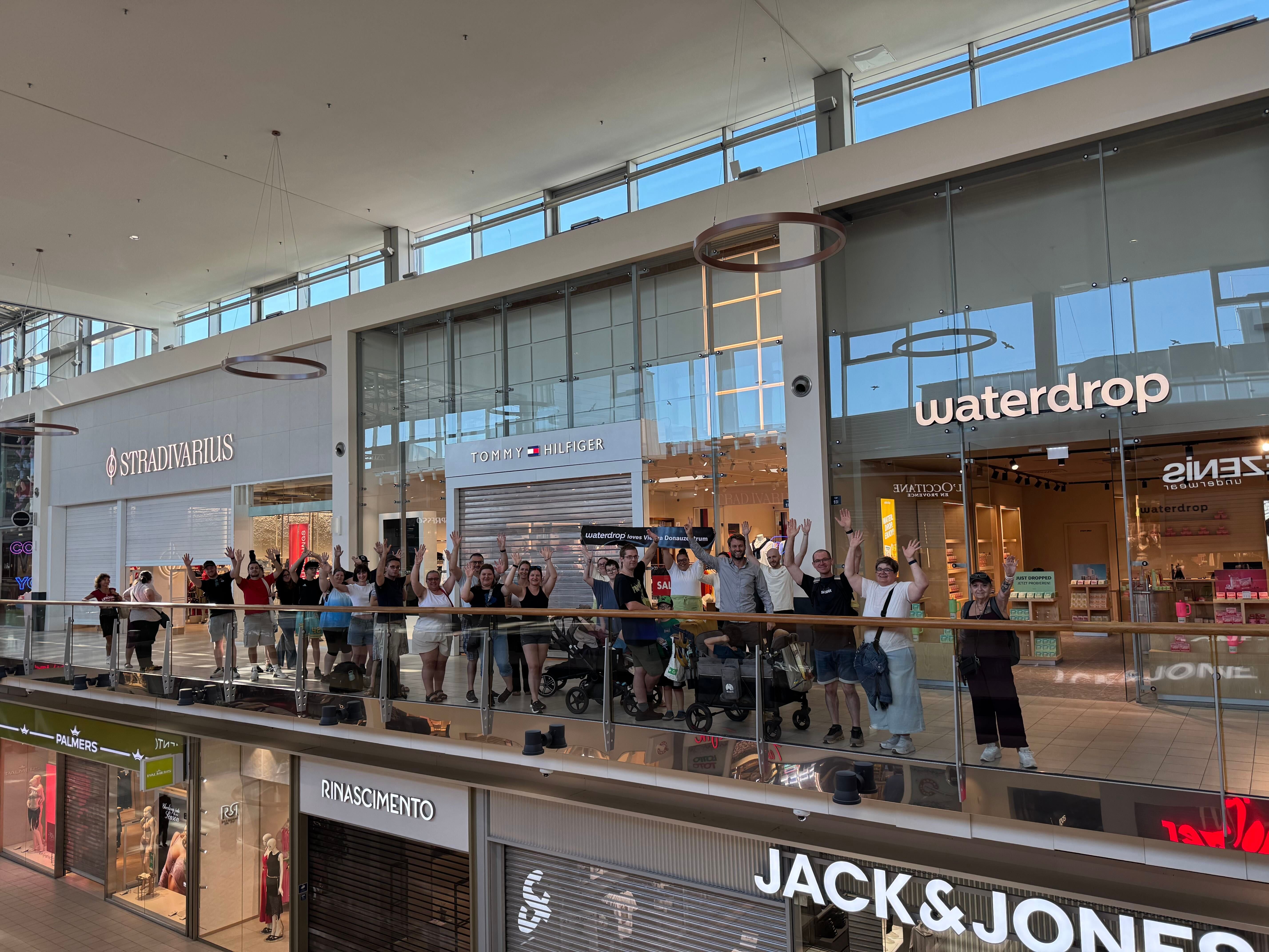 Menschen jubeln vor dem neu eröffneten Waterdrop-Store im Donauzentrum Einkaufszentrum.