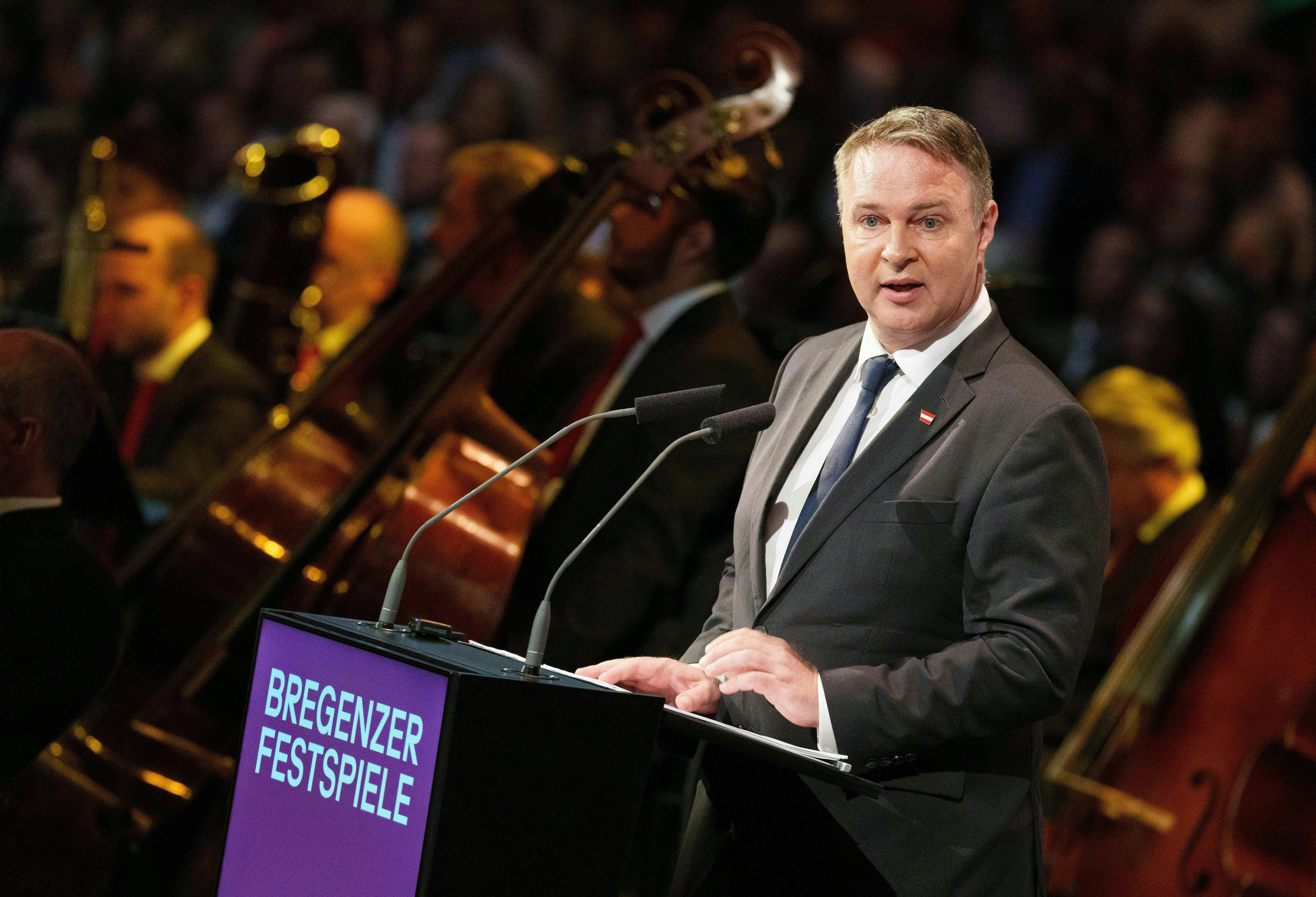 Ein Mann im Anzug spricht bei der Eröffnung der Bregenzer Festspiele am Rednerpult.