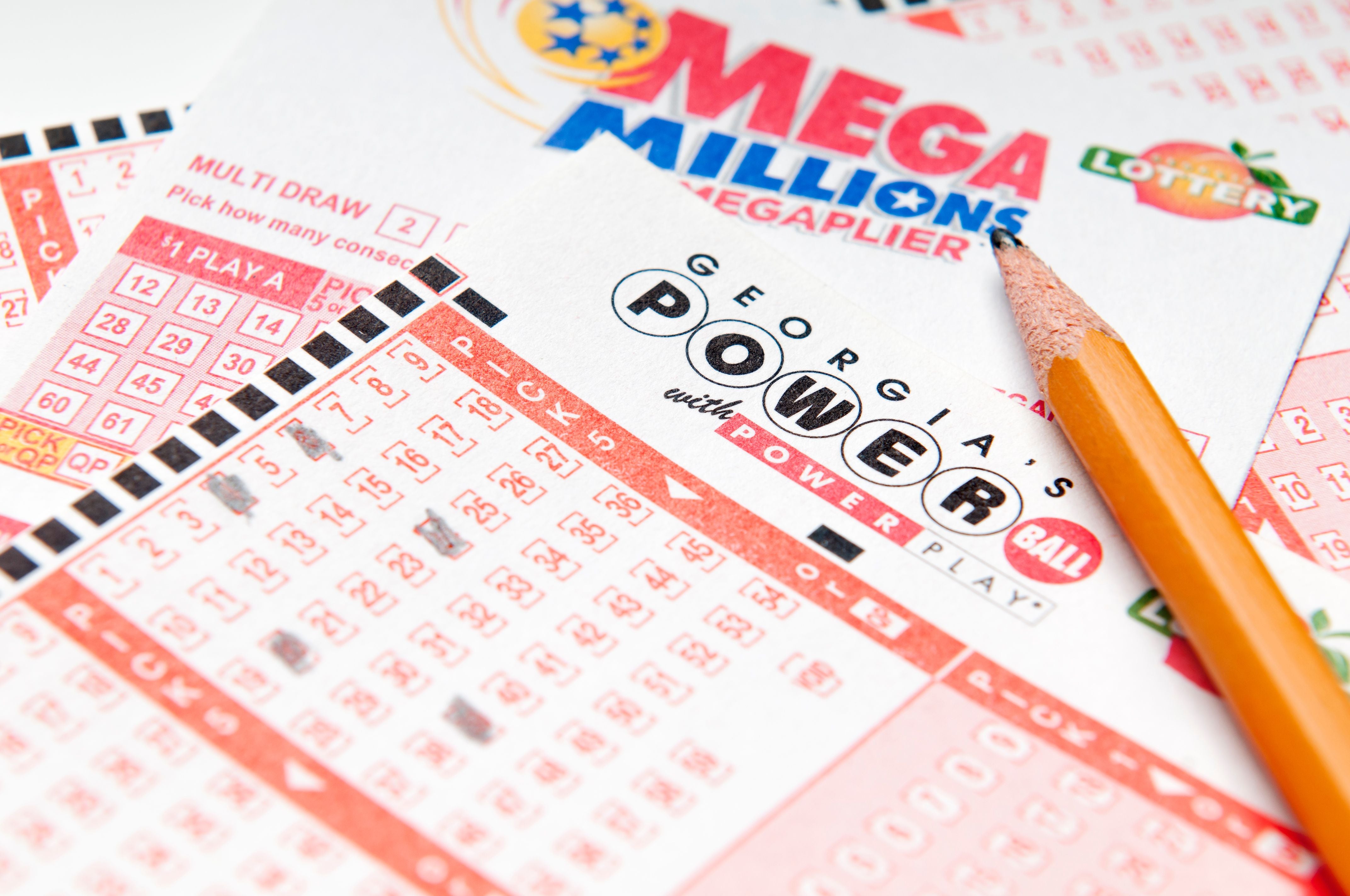 Mehrere US-Lotteriescheine von Powerball und Mega Millions mit einem Bleistift darauf.